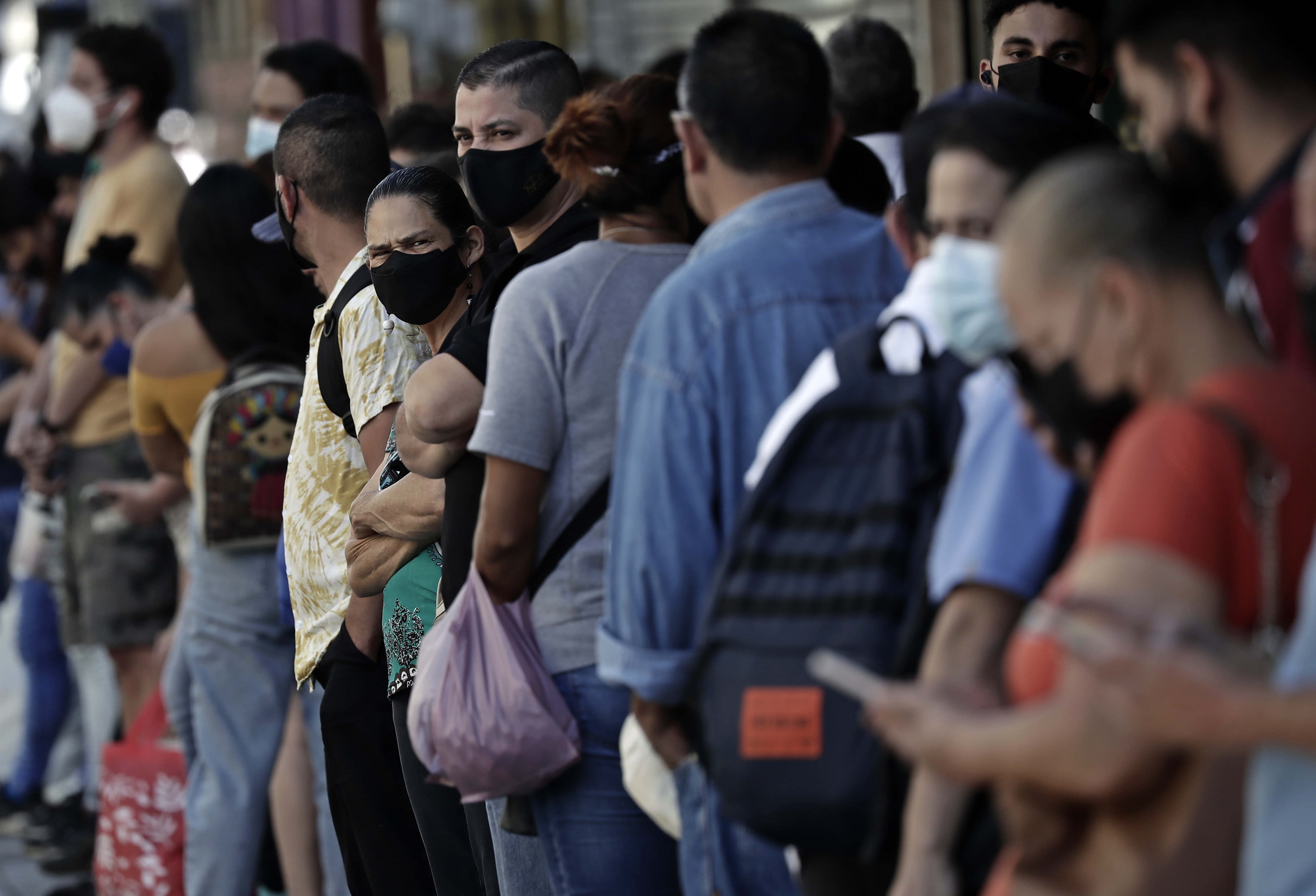 AME073. SAN JOSÉ (COSTA RICA), 21/01/2022.- Personas hacen fila para esperar el autobus, el 20 de enero de 2022, en San José (Costa Rica). La variante ómicron ha disparado los casos de la covid-19 en Centroamérica, donde se ven filas de personas en busca de diagnóstico en países como El Salvador o Panamá, aunque sin el fuerte impacto en las hospitalizaciones y muertes que han tenido olas previas de la pandemia. La Organización Panamericana de la Salud (OPS) afirmó el miércoles que los casos de la covid-19 se han duplicado en Panamá, Costa Rica y Honduras durante la última semana, países estos donde las autoridades han confirmado la presencia de la ómicron, lo mismo que en El Salvador y Guatemala. EFE/ Jeffrey Arguedas