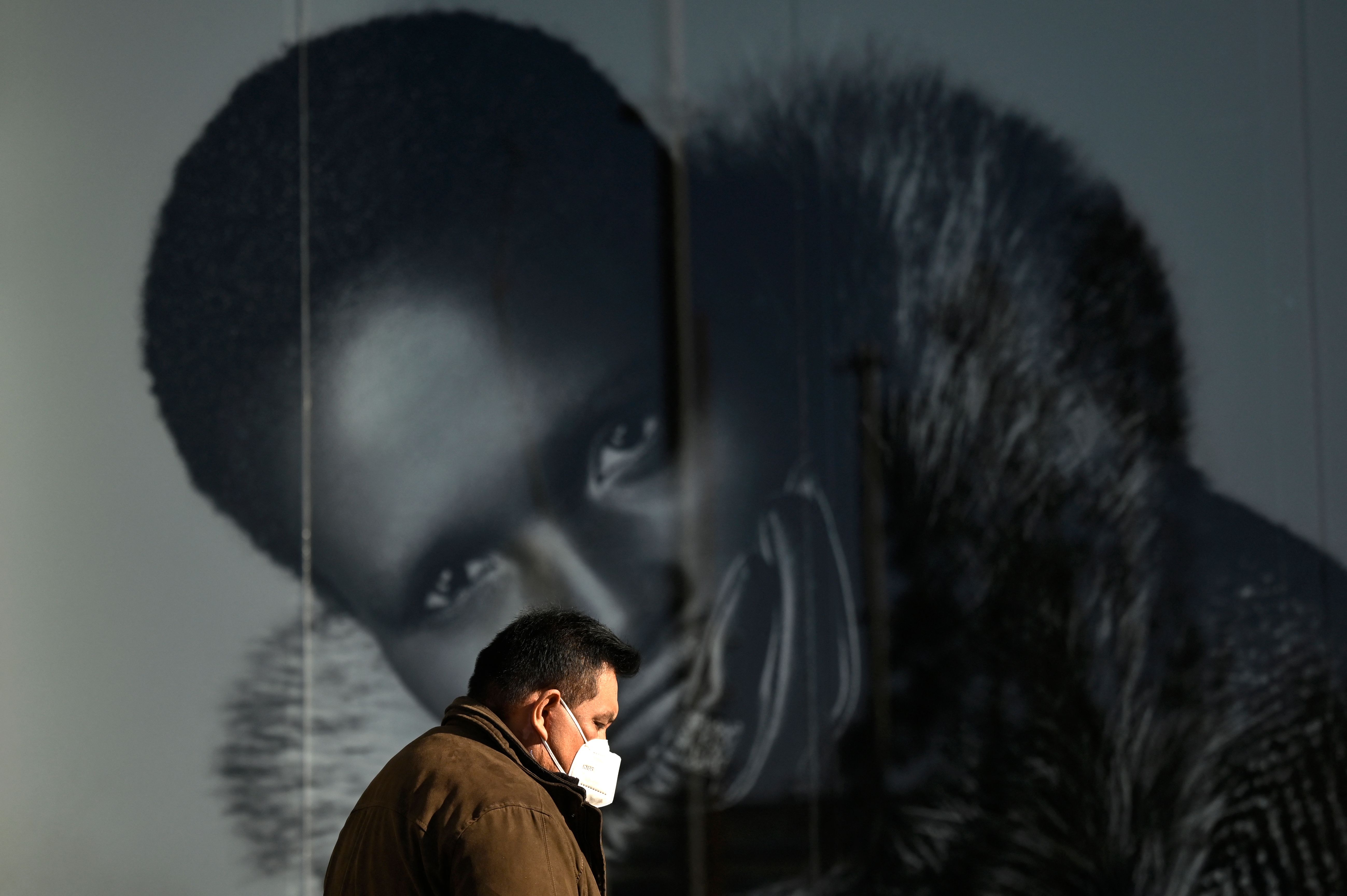 A man wearing a face mask walks in a street in Madrid on January 27, 2022. - Spain's northeastern Catalonia region is dropping the requirement for a Covid passport to enter restaurants, bars and gyms after experts found it was ineffective to halt surging Omicron cases. (Photo by Gabriel BOUYS / AFP)