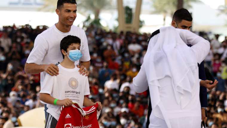 El delantero portugués del Manchester United, Cristiano Ronaldo posa con un niño en el al-Wasl Dome, durante su visita a la Expo 2020, en Dubai. Foto Prensa Libre: AFP.