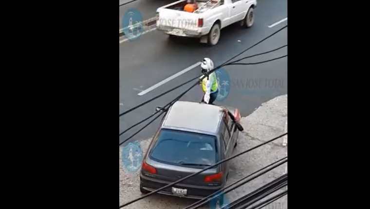 Un agente de la PMT fue llevado en el capó de un vehículo en un sector de la zona 4 de la capital. (Foto Prensa Libre: Captura de Pantalla)