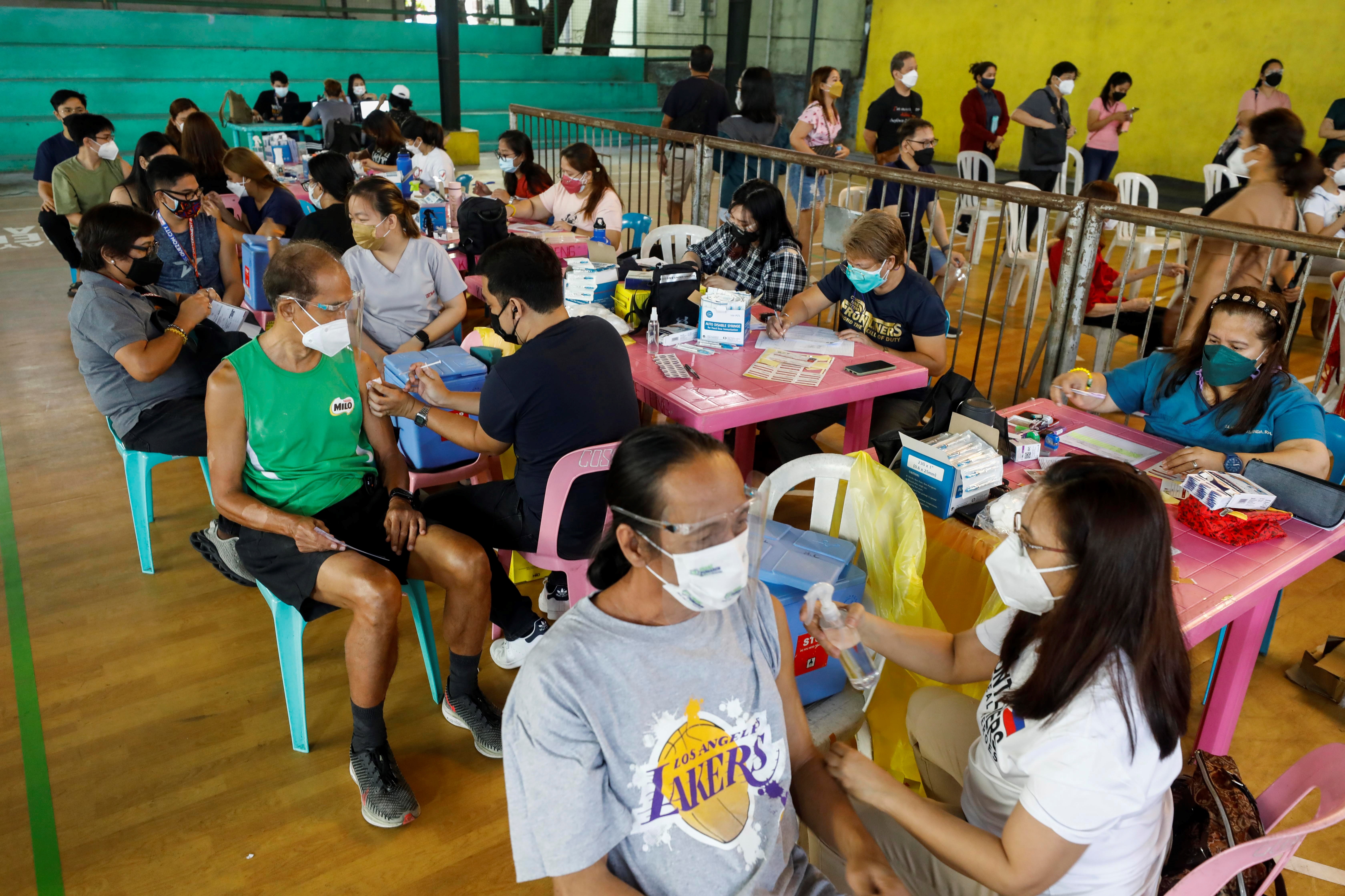 Filipinos reciben la vacuna contra el coronavirus durante una jornada de vacunación. Recibir la dosis anticovid en este país es voluntario, pero quienes no estén vacunados no pueden salir de sus casas. (Foto Prensa Libre: AFP)