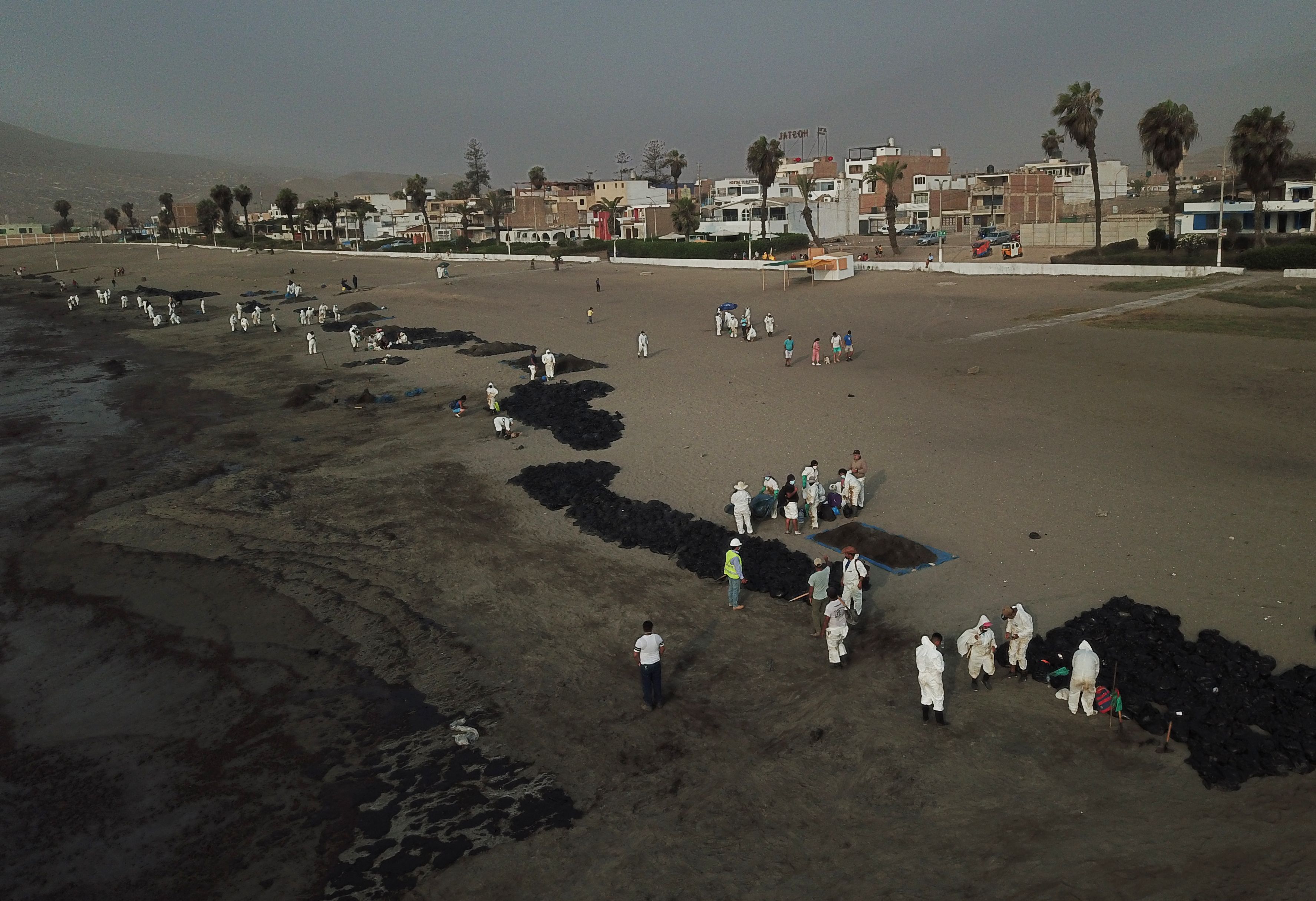 Vista aérea de los equipos de limpieza que trabajan para retirar el petróleo de una playa anexa a la ciudad turística de verano de Ancón, en el norte de Lima, el 20 de enero de 2022 después de un derrame ocurrido durante el proceso de descarga del buque tanque de bandera italiana "Mare Doricum" en La Refinería de Pampilla provocada por el oleaje anormal registrado tras la erupción volcánica en Tonga.  (Foto Prensa Libre: AFP)