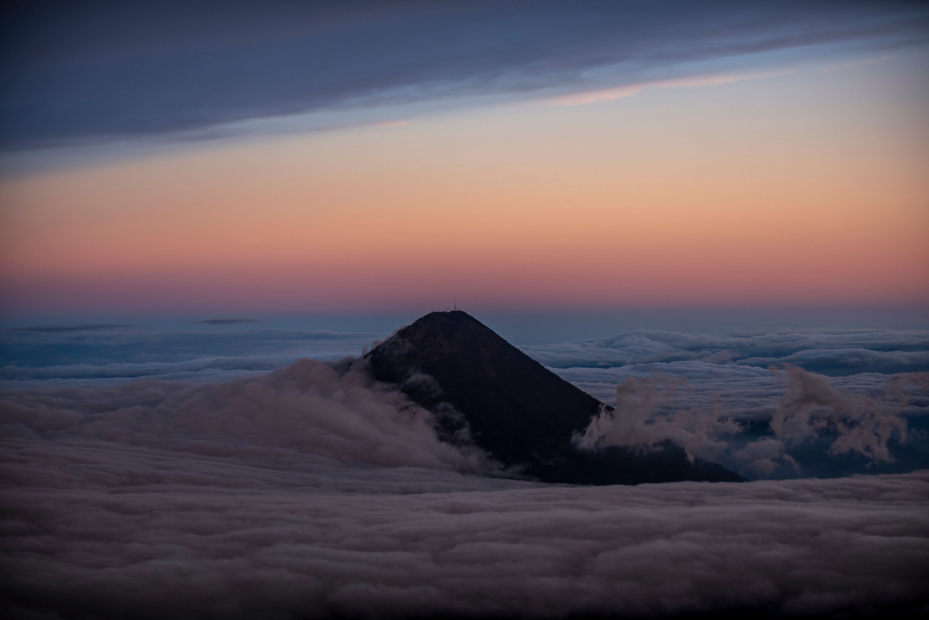 La cumbre del Volcán de Agua se eleva sobre las nubes en una panorámica captada desde el Volcán Acatenango, 75 km al suroeste de Ciudad de Guatemala, el 12 de enero de 2022. (Foto Prensa Libre: AFP)