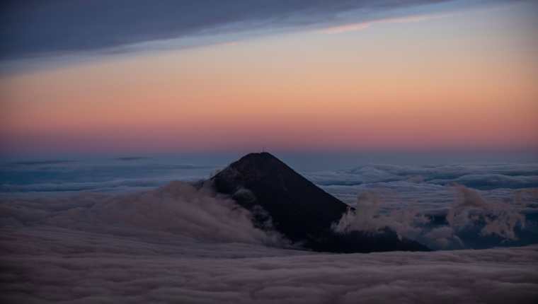 La cumbre del Volcán de Agua se eleva sobre las nubes en una panorámica captada desde el Volcán Acatenango, 75 km al suroeste de Ciudad de Guatemala, el 12 de enero de 2022. (Foto Prensa Libre: AFP)