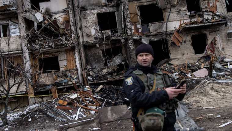 Un oficial de policía ucraniano se encuentra frente a un bloque residencial dañado por un ataque con misiles.