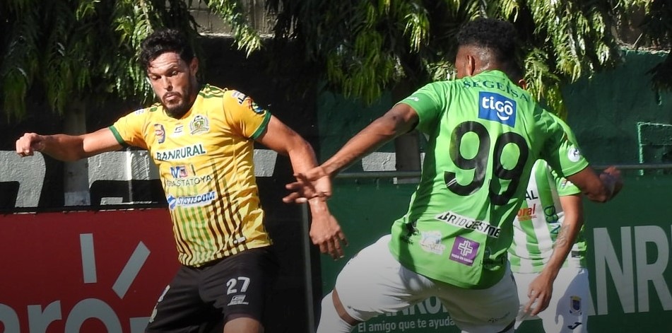 El jugador de Guastatoya, Luis Landín (amarillo) disputa el balón a Romario da Silva de Antigua. (Foto Prensa Libre: Facebook)