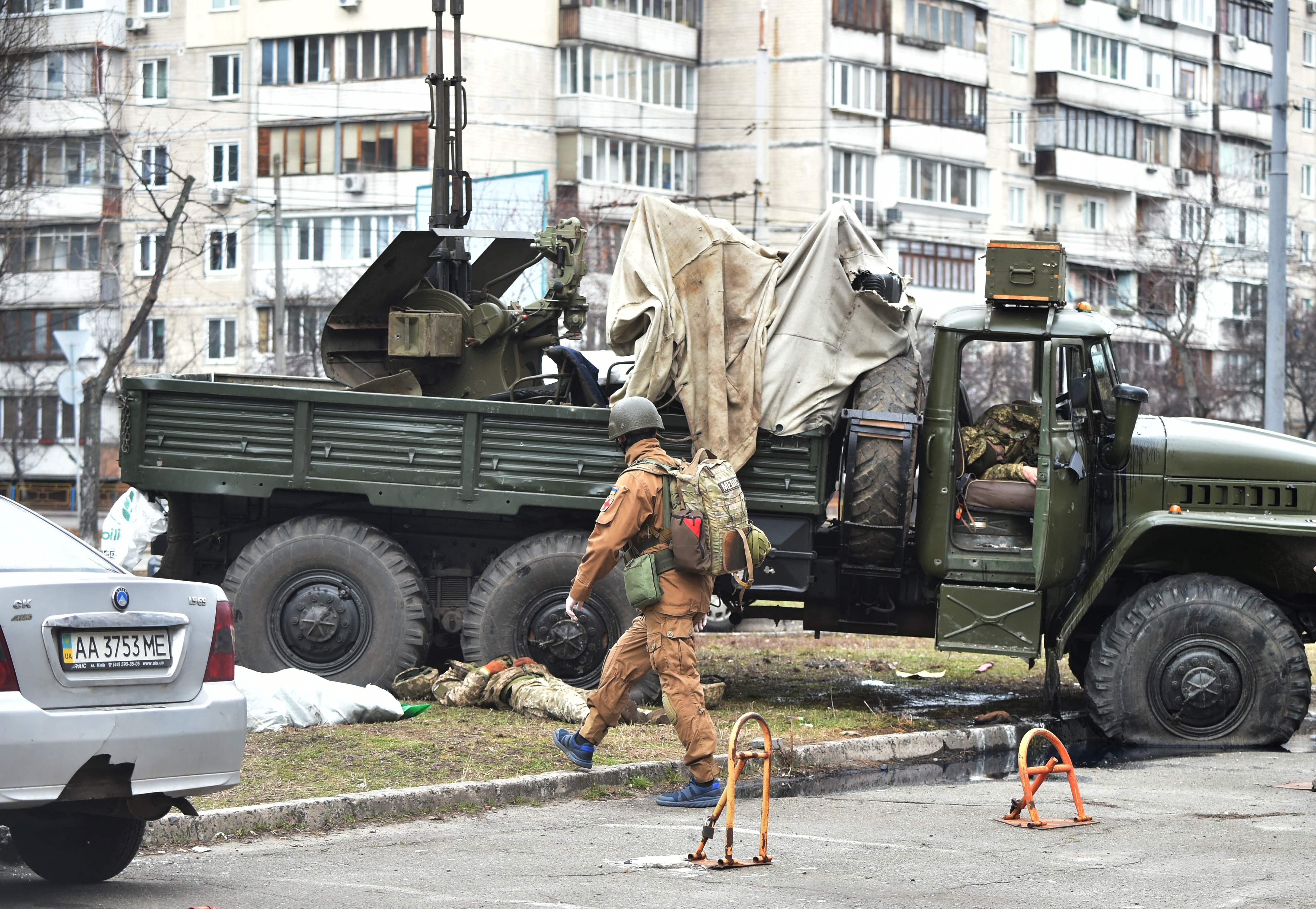 Un médico militar de Ucrania se aproxima a los cadáveres de  militares rusos que vestían un uniforme de servicio ucraniano que yacían al lado y dentro de un vehículo después de que un grupo de asalto recibió disparos en la capital ucraniana de Kiev el 25 de febrero.  (Foto Prensa Libre: AFP)