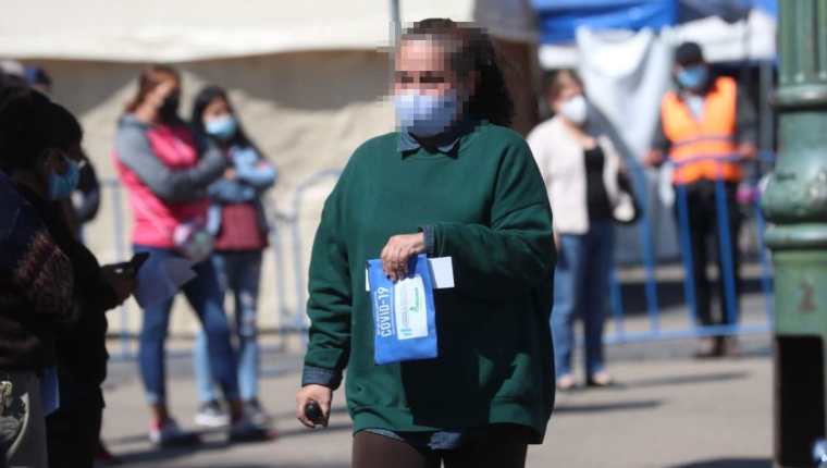 Una mujer que dio positivo al covid-19 sale con su kit de medicamentos luego de hacerse la prueba en la Plaza de Constitución en Guatemala. (Foto Prensa Libre: Érick Ávila)