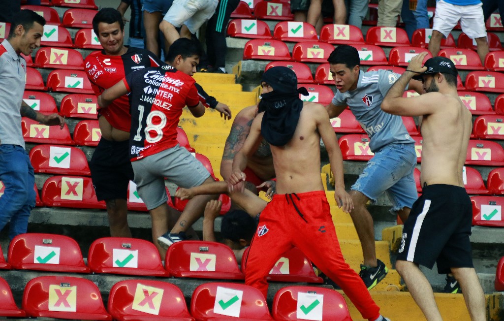 Supporters of Atlas fight with supporters of Queretaro during the Mexican Clausura tournament football match between Queretaro and Atlas at Corregidora stadium in Queretaro, Mexico on March 5, 2022. - Due to an outbreak of violence that spilled onto the field, the match between the 'Gallos Blancos' of Querétaro and the 'Zorros' of Atlas, for the ninth round of the Clausura-2022 Mexican soccer tournament at the La Corregidora stadium, in the city of Querétaro (downtown), was suspended. (Photo by EDUARDO GOMEZ / AFP)