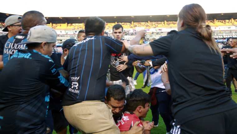 Momentos del hecho violento acontecido el sábado entre aficionados de Querétaro y Atlas. (Foto Prensa Libre: AFP) 