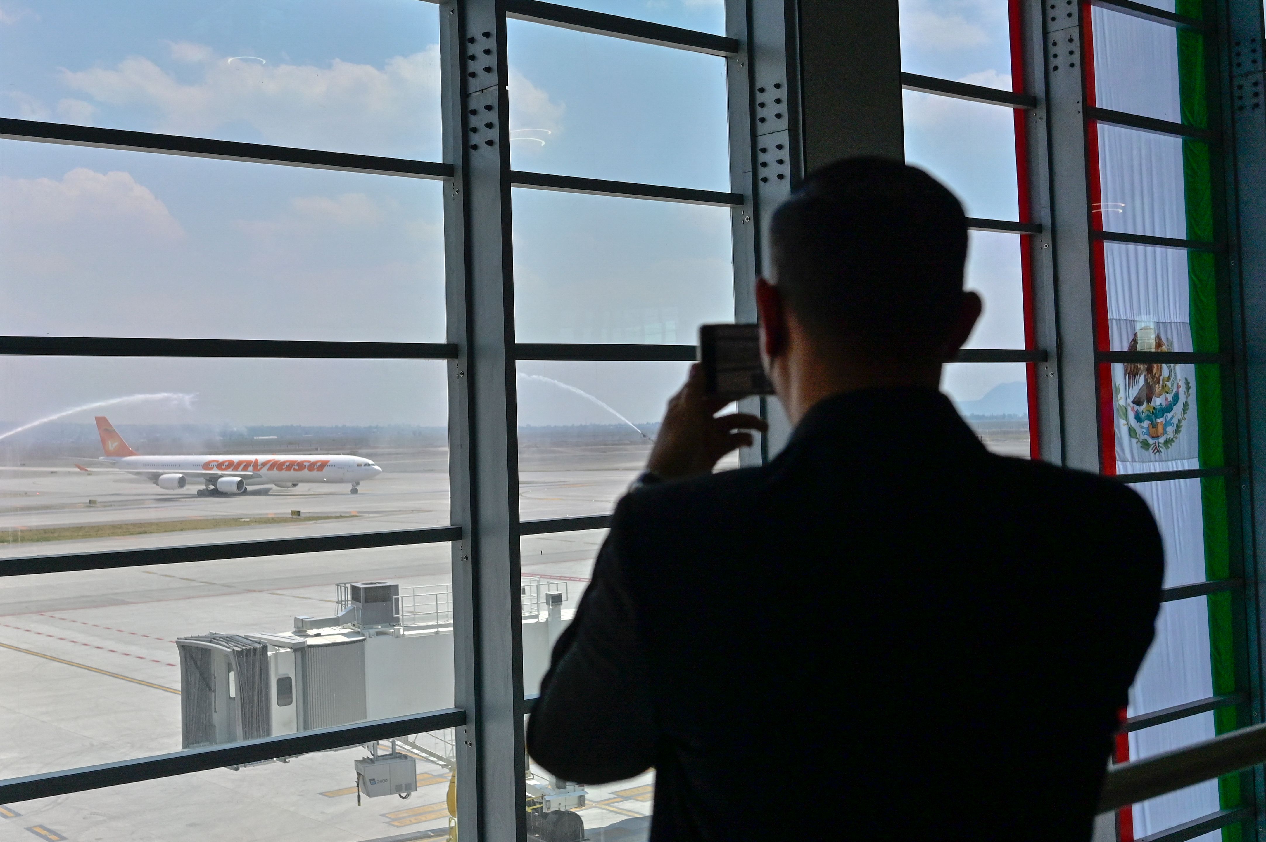 Un hombre toma una foto de un avión en el aeropuerto internacional Felipe Ángeles de México. (Foto Prensa Libre: Pedro Pardo / AFP)