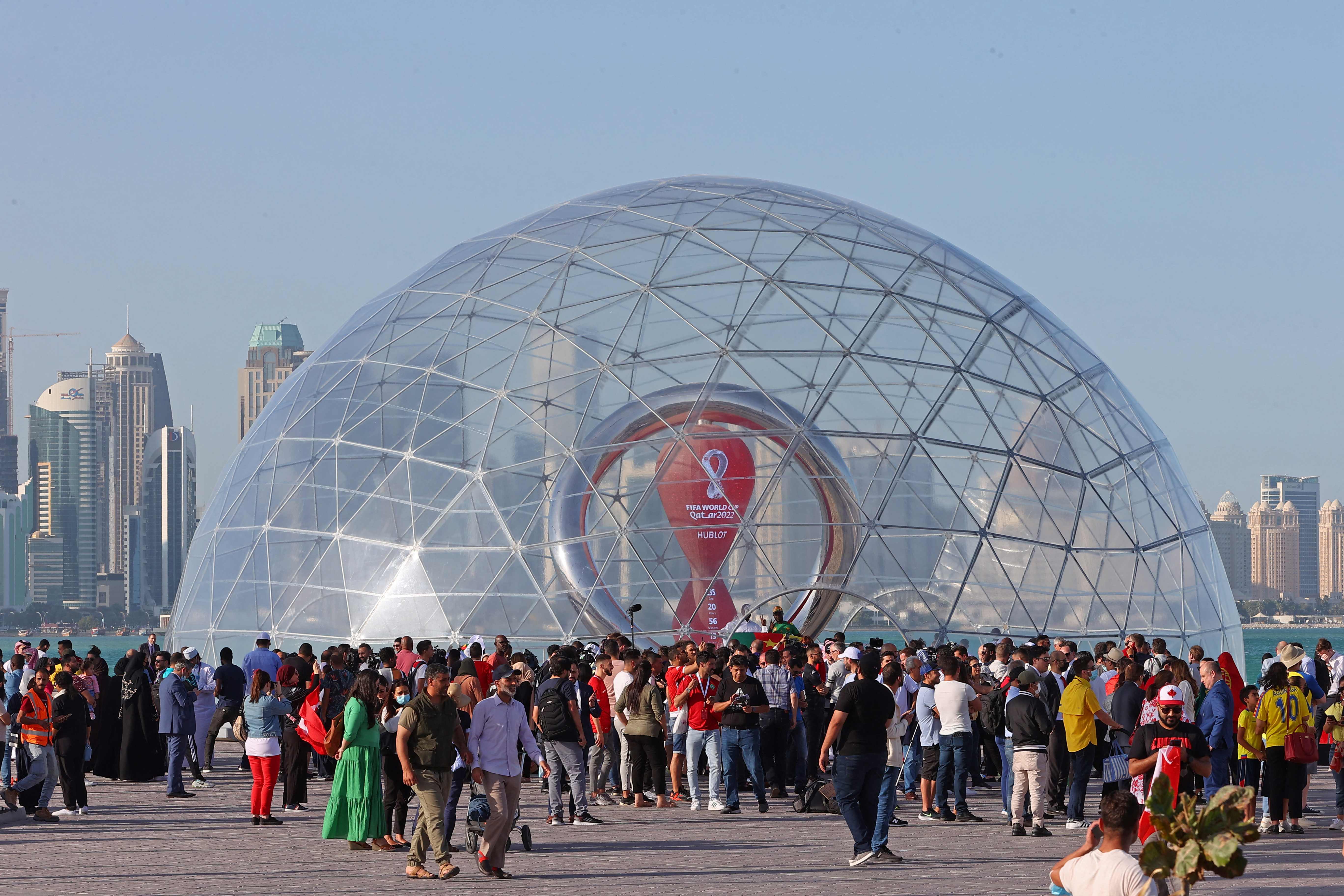 La gente se reúne frente al reloj de cuenta regresiva para la Copa del Mundo de 2022 en el paseo marítimo de la capital de Qatar, Doha, el 30 de marzo de 2022. (Foto Prensa Libre: AFP).