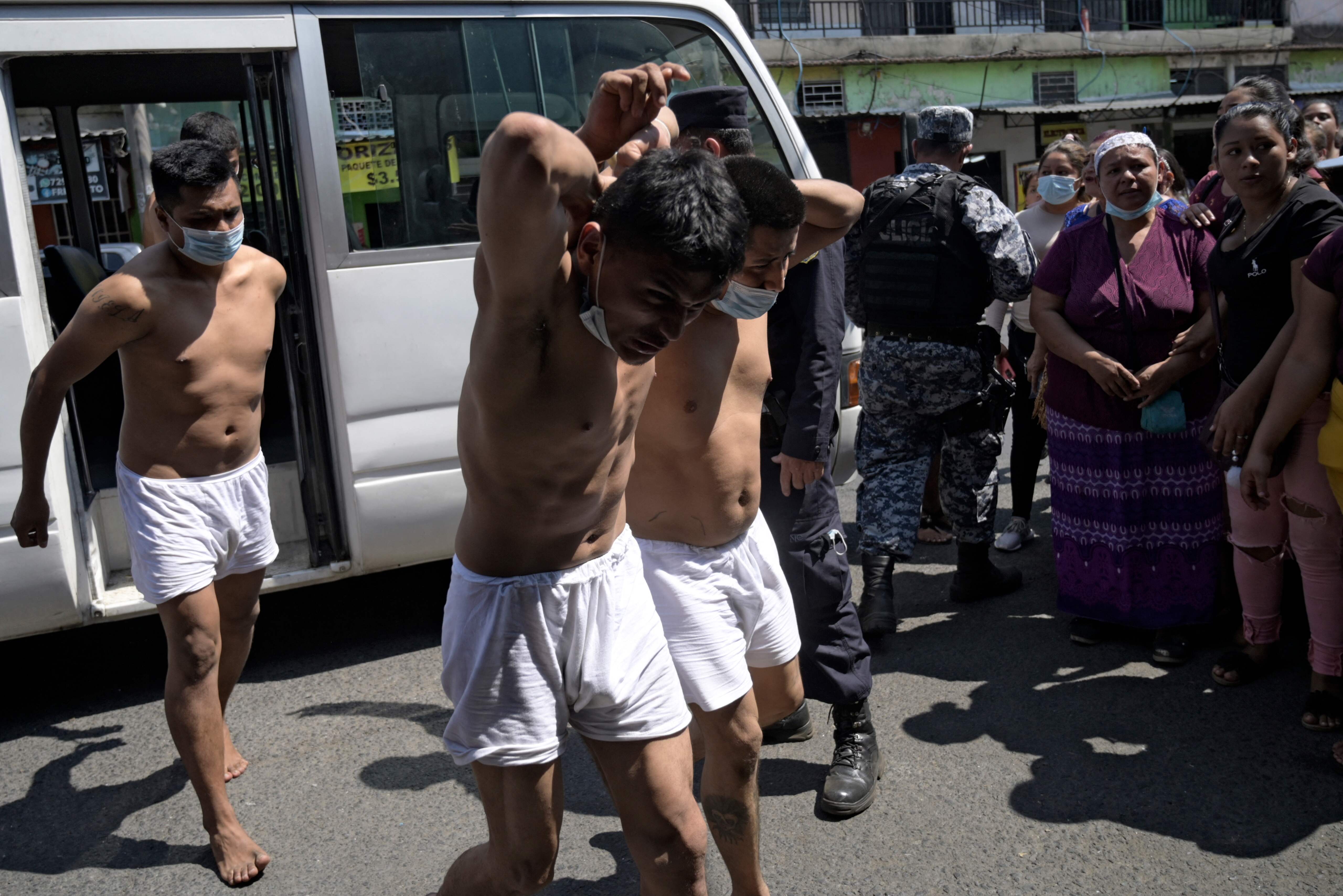 Hombres capturados por supuestos vínculos con pandillas son escoltados por la Policía Nacional Civil durante el estado de emergencia declarado por el gobierno en San Salvador. Foto Prensa Libre: AFP.
