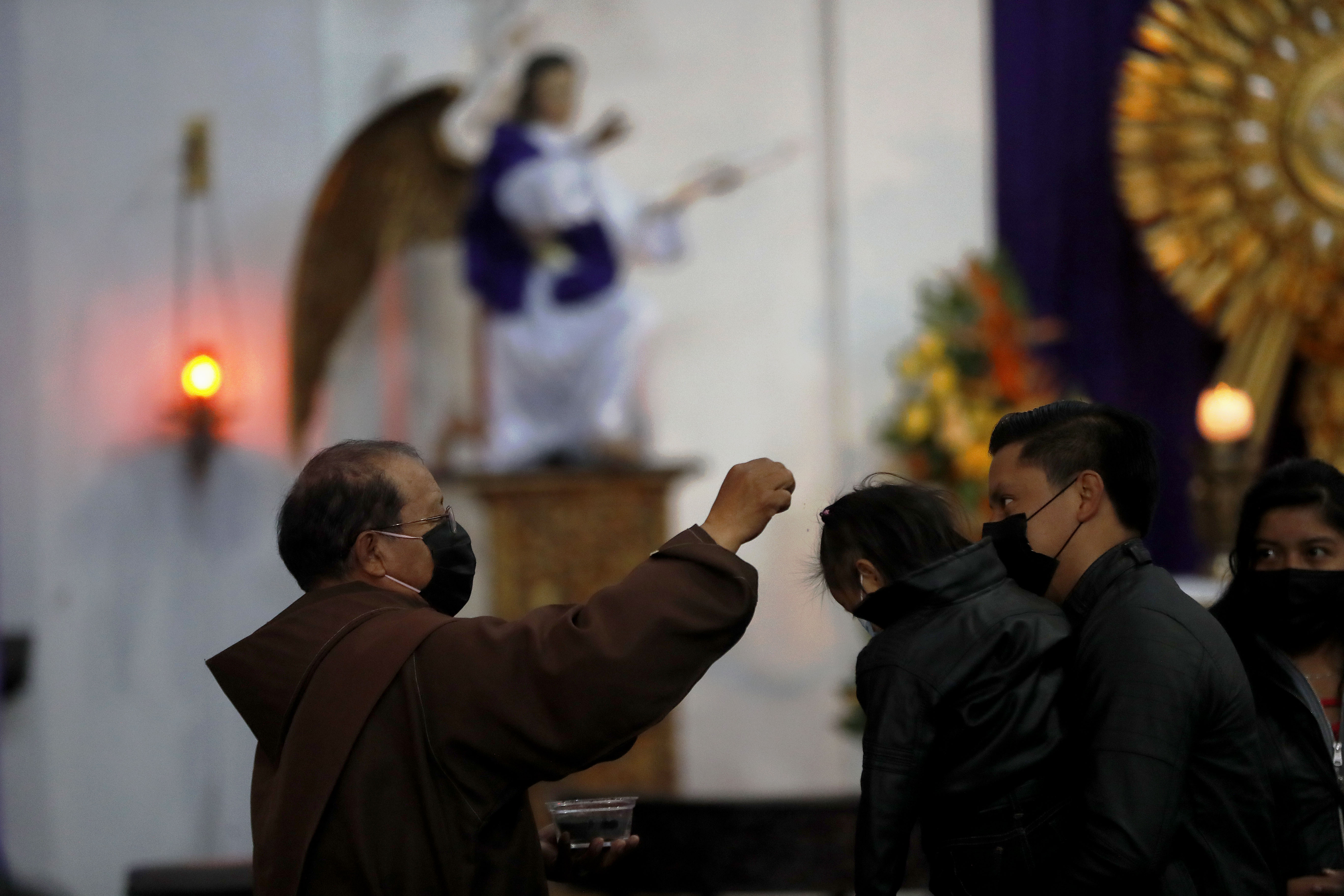 Fieles reciben las cenizas en la cabeza para evitar el contacto con los dedos en la frente por el Covid-19, durante el Miércoles de Ceniza en la iglesia La Merced, Antigua Guatemala. (Foto Prensa Libre: EFE)