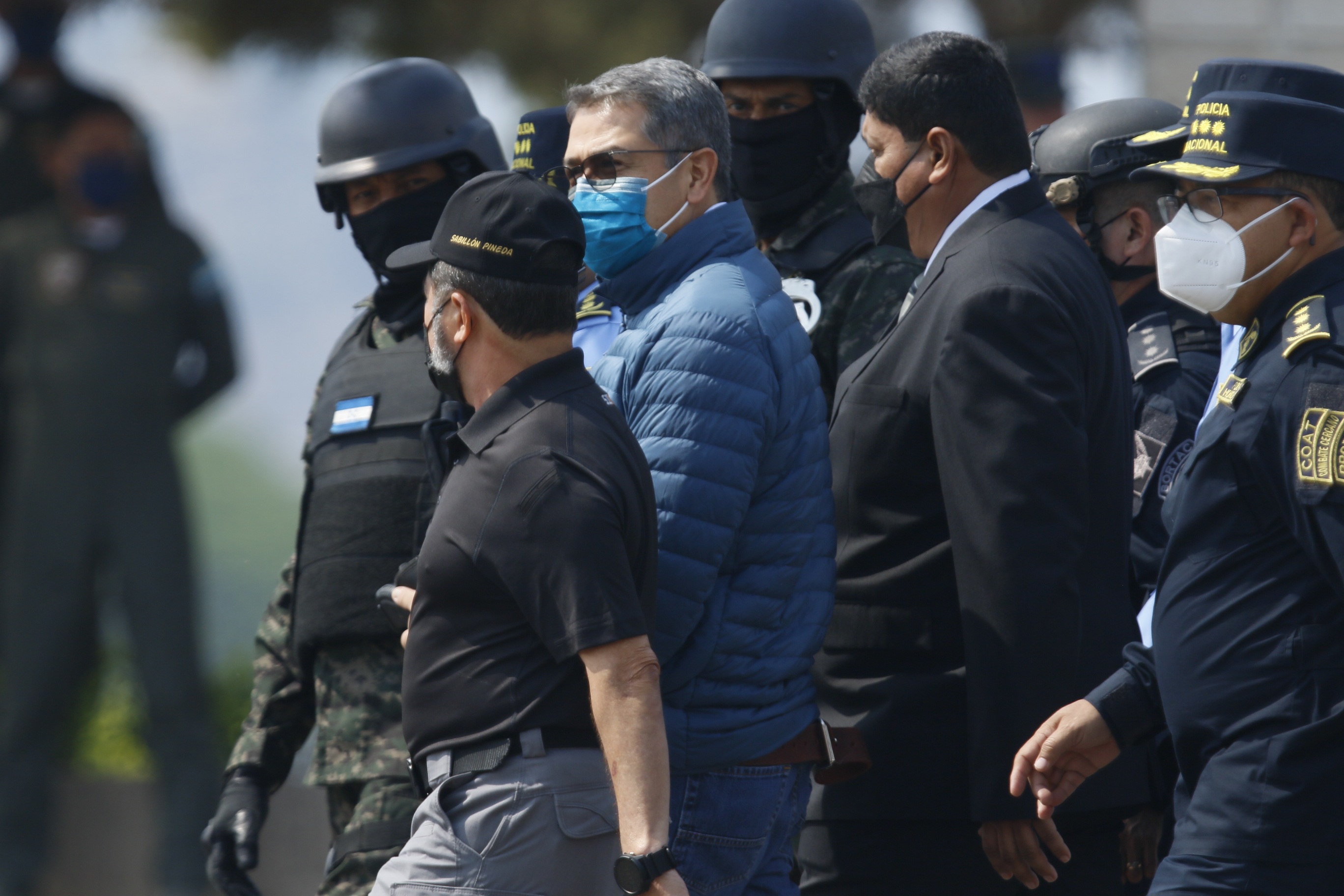 HON01. TEGUCIGALPA (HONDURAS), 21/04/2022.- El expresidente hondureño Juan Orlando Hernández es dirigido a la aeronave que lo llevará extraditado a los Estados Unidos hoy, en la base aérea Hernán Acosta de Tegucigalpa (Honduras). EFE/ Humberto Espinoza