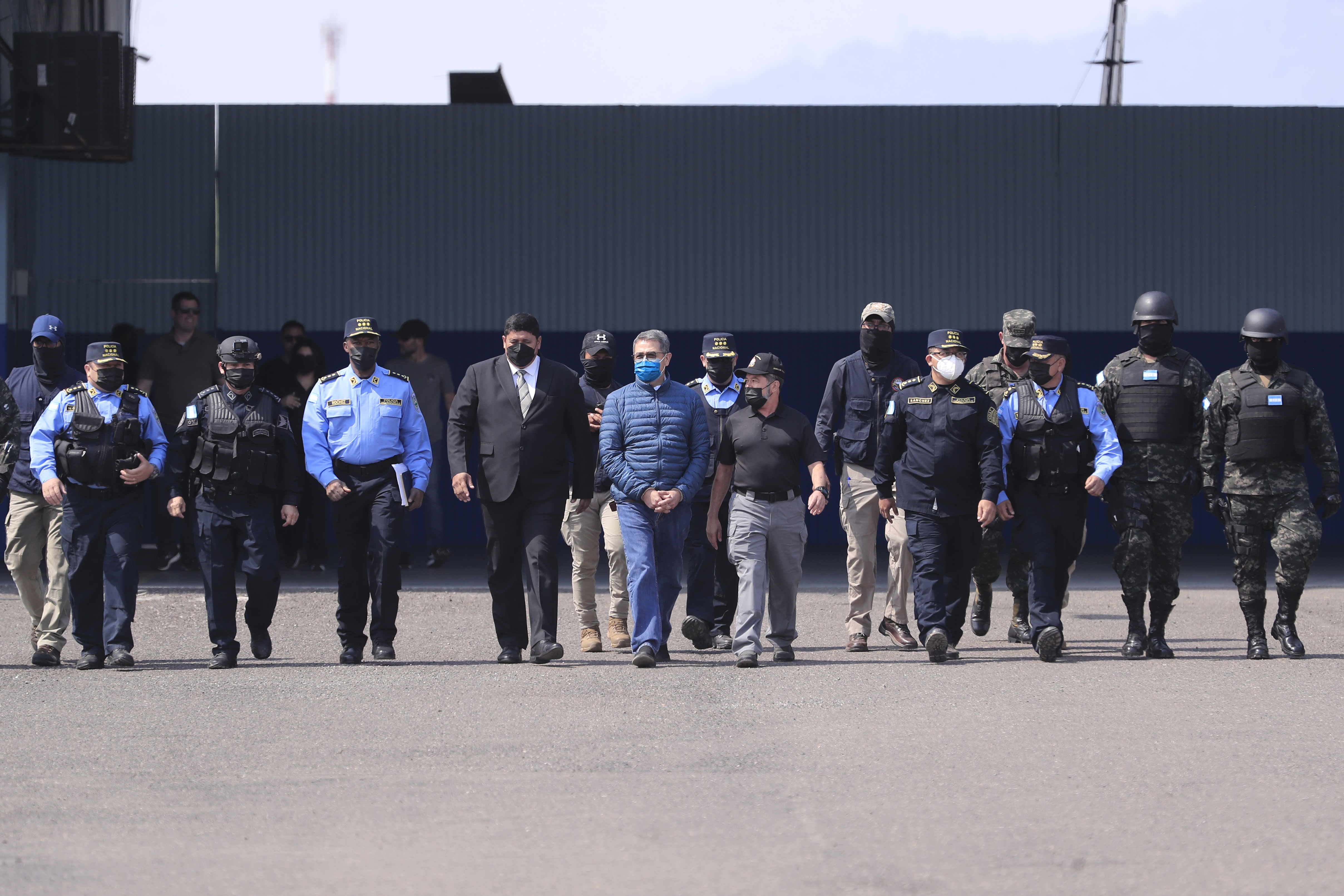 HON01. TEGUCIGALPA (HONDURAS), 21/04/2022.- El expresidente hondureño Juan Orlando Hernández es dirigido a la aeronave que lo llevará extraditado a los Estados Unidos hoy, en la base aérea Hernán Acosta de Tegucigalpa (Honduras). EFE/ Gustavo Amador