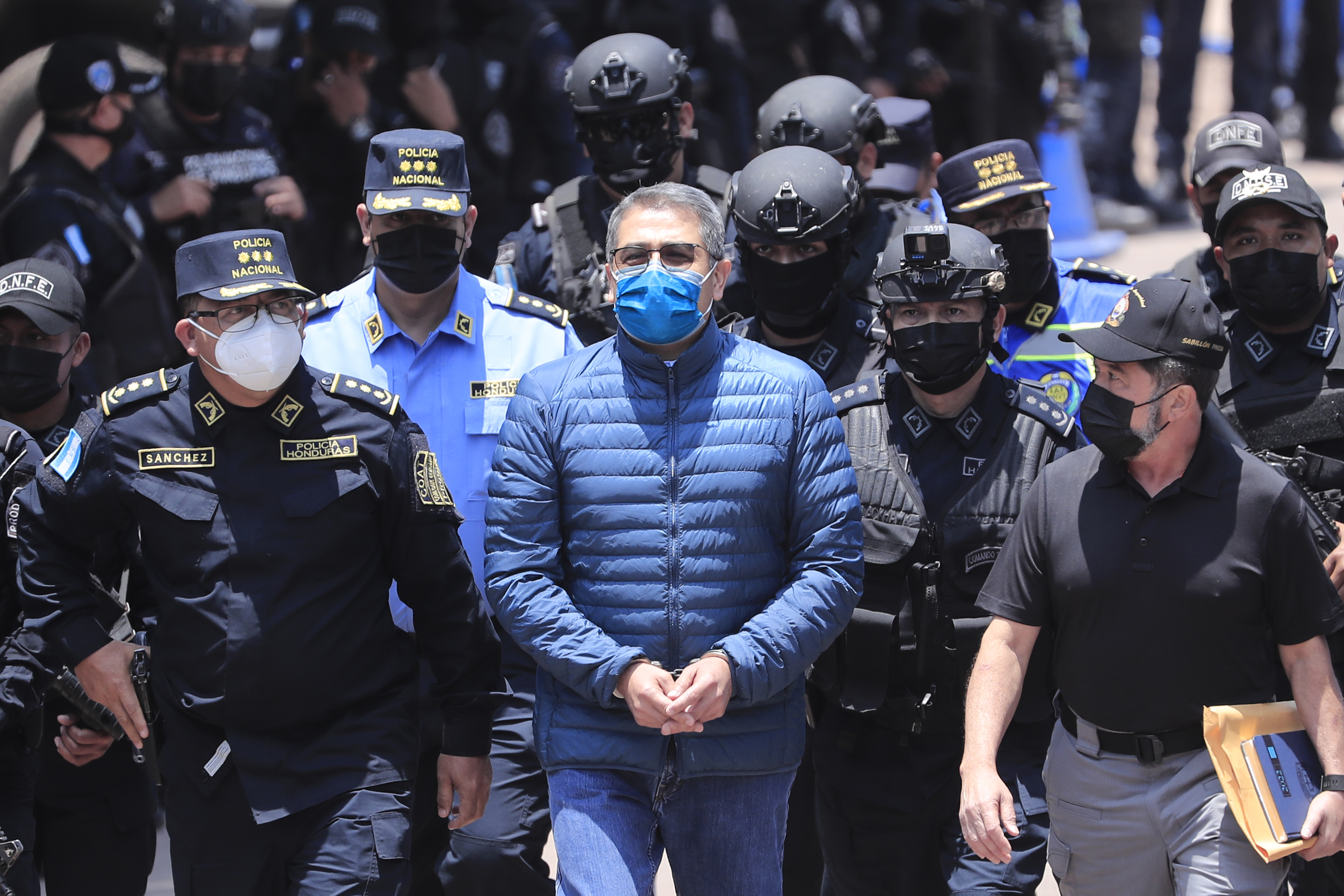 Policías custodian al expresidente hondureño Juan Orlando Hernández (c) rumbo a su extradición en la sede de la Dirección Nacional Fuerzas Especiales, en Tegucigalpa. (Foto Prensa Libre: EFE)