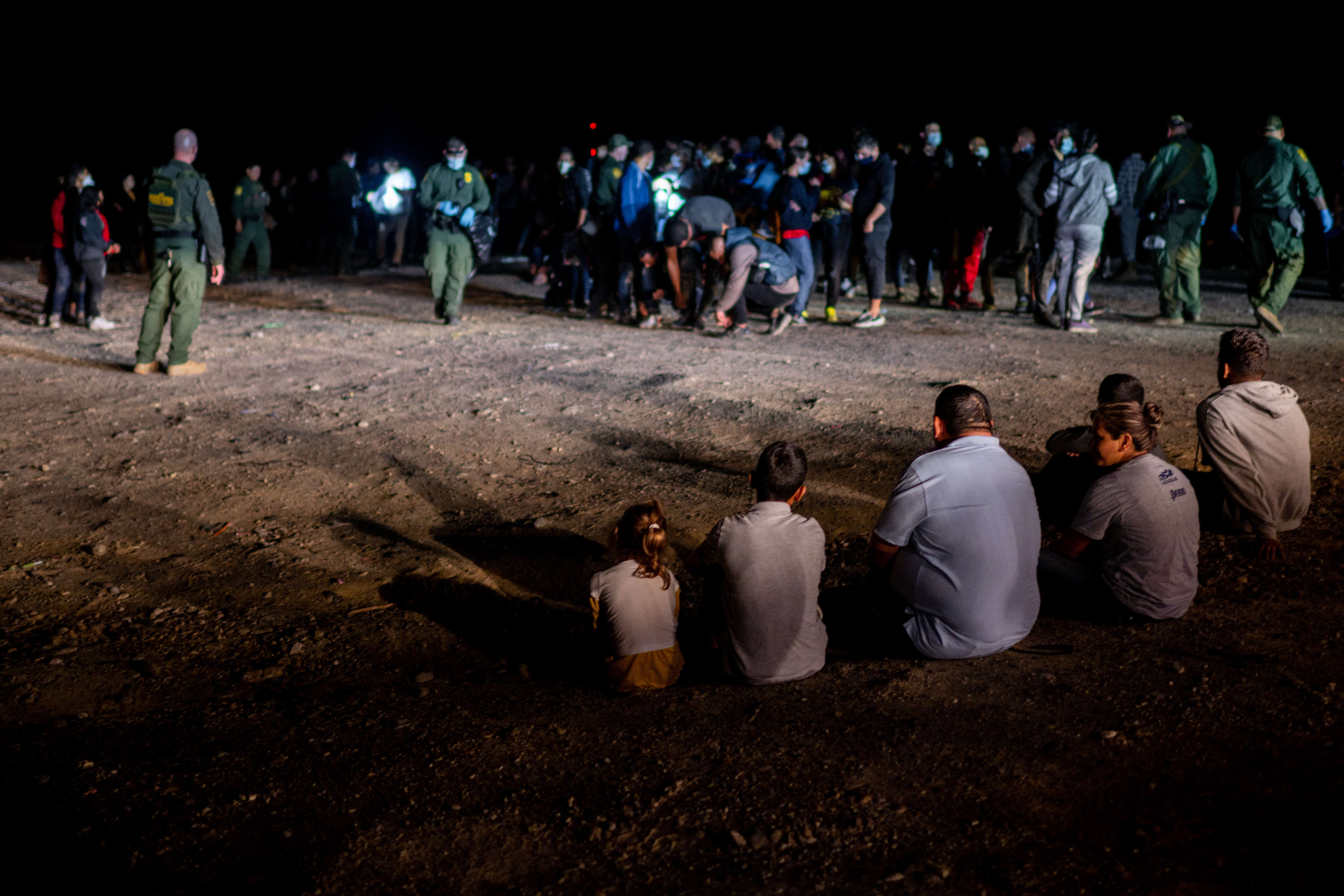 ROMA, TEXAS - MAY 05: A migrant family sits after being processed on May 05, 2022 in Roma, Texas. Texas Gov. Greg Abbott's 