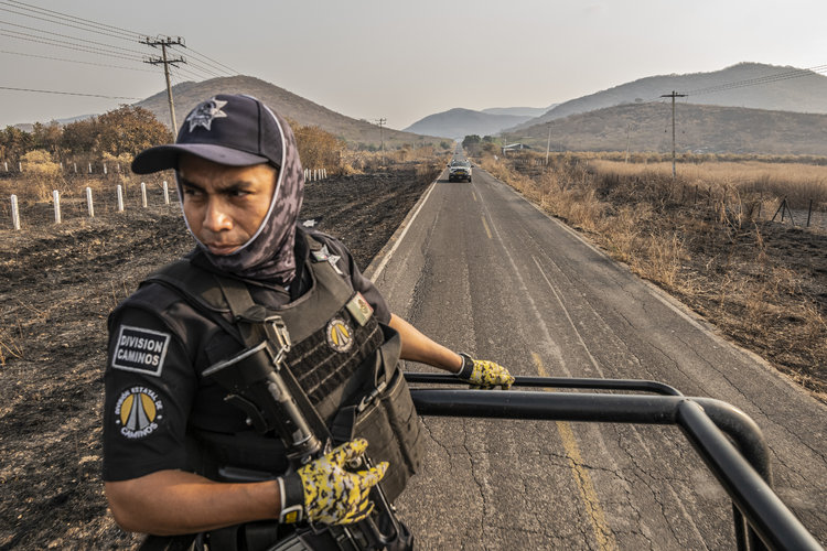 Una patrulla de policía pasa por delante de los campos quemados en el conflicto entre cárteles en El Limoncito, Michoacán, México, el 24 de febrero de 2022.  (Foto Prensa Libre: Daniel Berehulak/The New York Times)