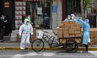 Workers wearing protective gear stack up boxes over a cart to deliver in a neighborhood during a Covid-19 coronavirus lockdown in the Jing'an district in Shanghai on May 18, 2022. (Photo by Hector RETAMAL / AFP)
