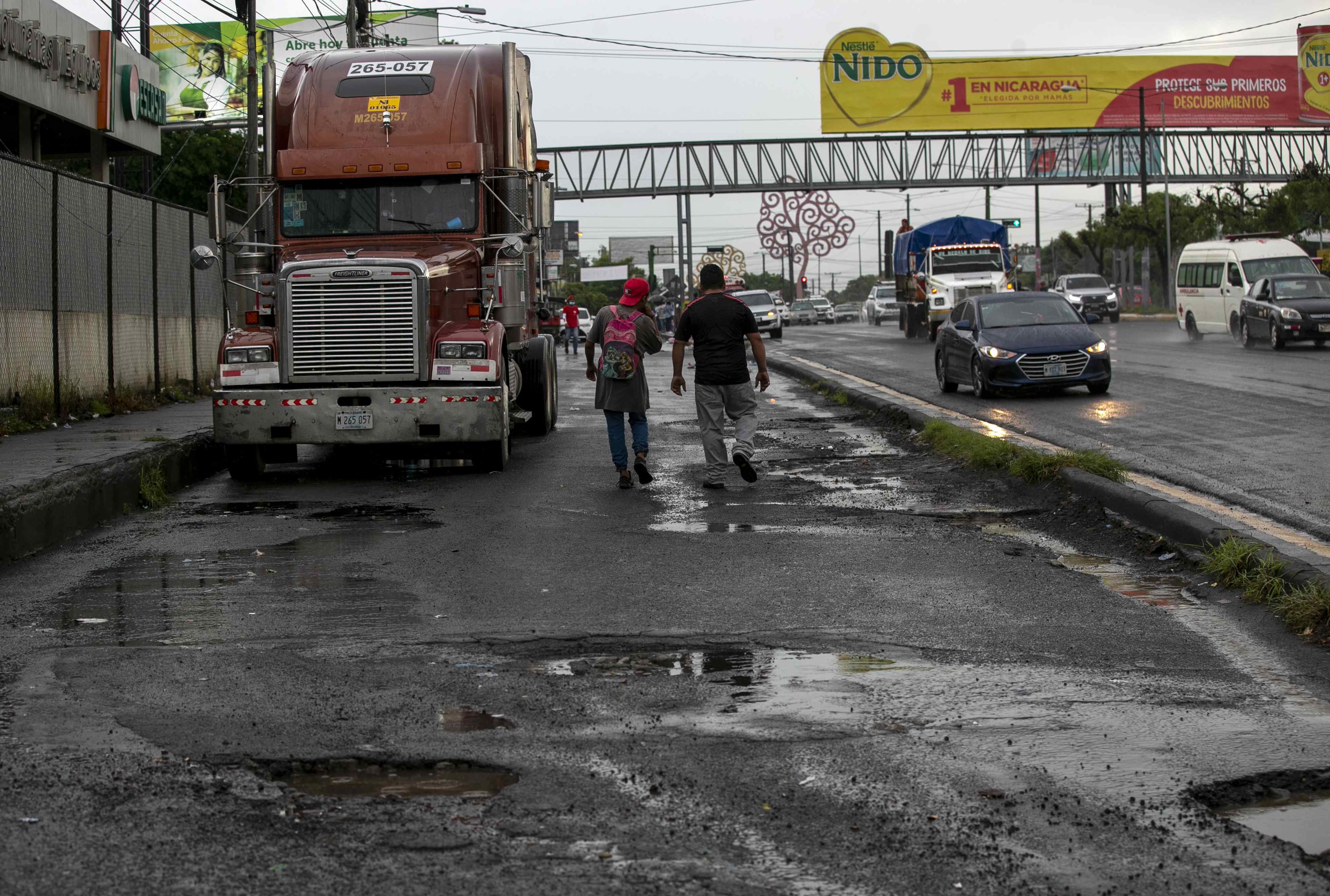 AME015. MANAGUA (NICARAGUA), 28/06/2022.- Dos hombres caminan hoy por una vía deteriorada, en Managua (Nicaragua). La Asamblea Nacional (Parlamento) de Nicaragua autorizó este martes al Ejecutivo gestionar un préstamo con el BCIE por un monto de 352,58 millones de dólares para financiar un programa de ampliación y mejoramiento de carreteras. EFE/Jorge Torres