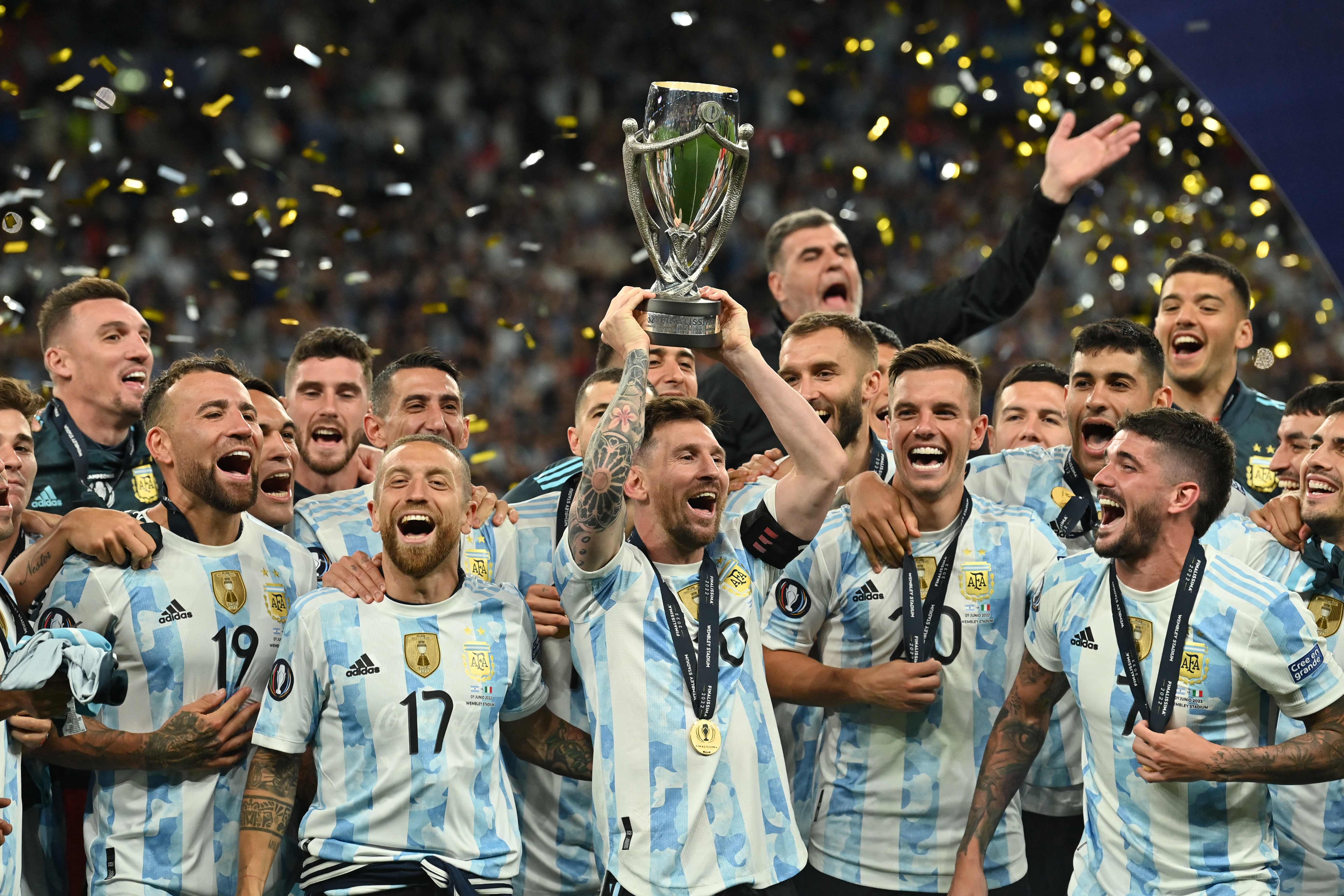 Argentina's striker Lionel Messi lifts the trophy as Argentina's players celebrate on the pitch after their victory in the 'Finalissima' International friendly football match between Italy and Argentina at Wembley Stadium in London on June 1, 2022. - The Azzurri face the South American continental champions in the inaugural Finalissima at Wembley. (Photo by Glyn KIRK / AFP)