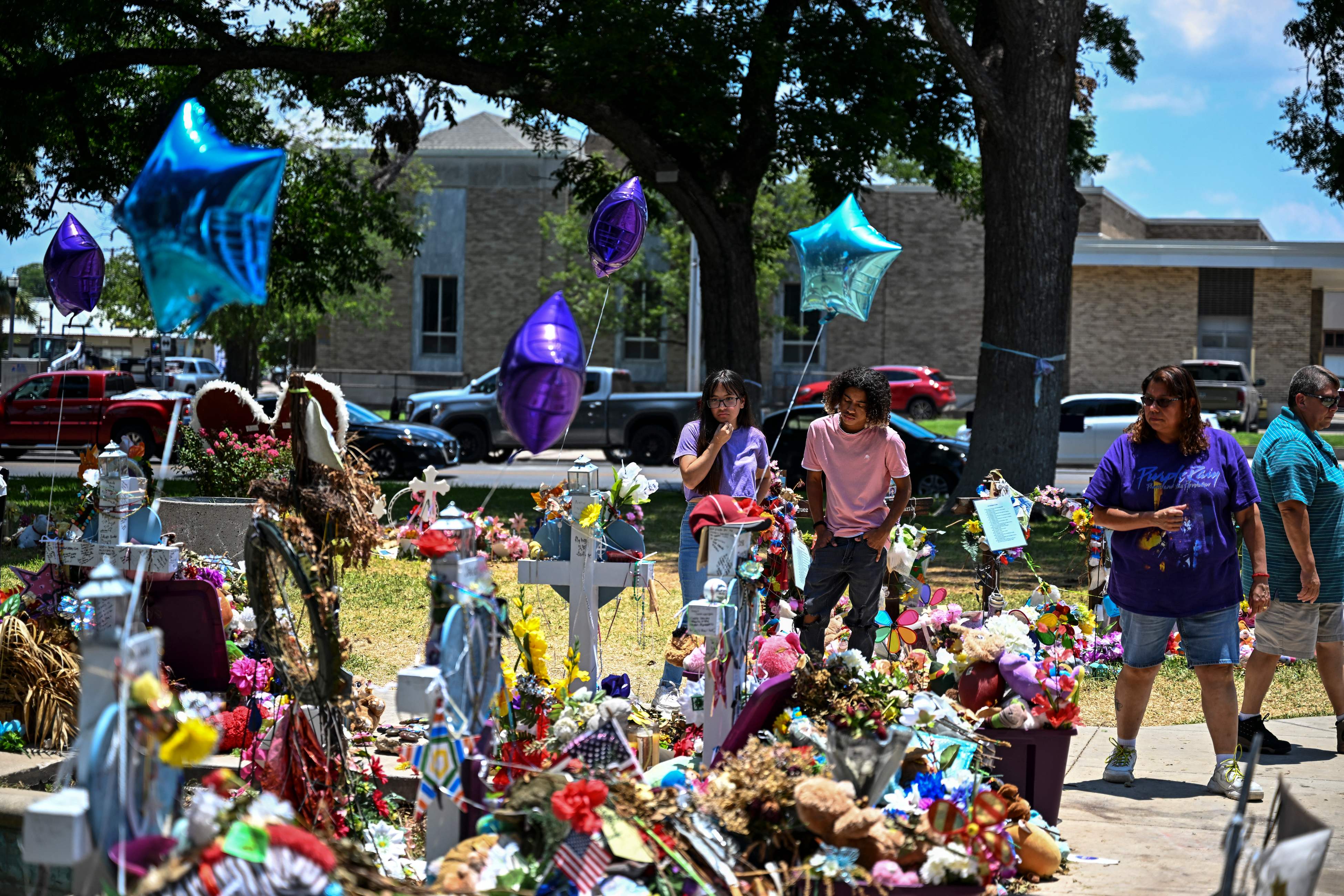 People visit a makeshift memorial to the victims of a shooting at Robb Elementary School in Uvalde, Texas, on June 30, 2022. - Nineteen young children and two teachers were killed when a teenage gunman went on a rampage at Robb Elementary on May 24 in America's worst school shooting in a decade. (Photo by CHANDAN KHANNA / AFP)