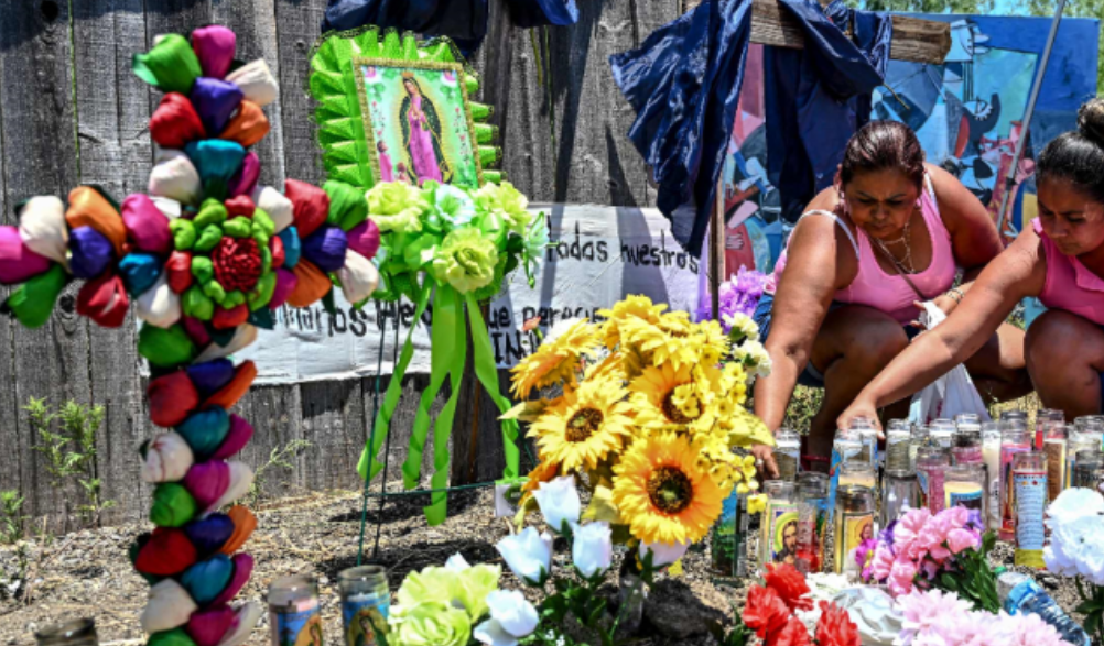 Personas colocan flores y velas en un monumento improvisado donde se descubrió un camión con migrantes fallecidos en Texas. (Foto Prensa Libre: AFP)