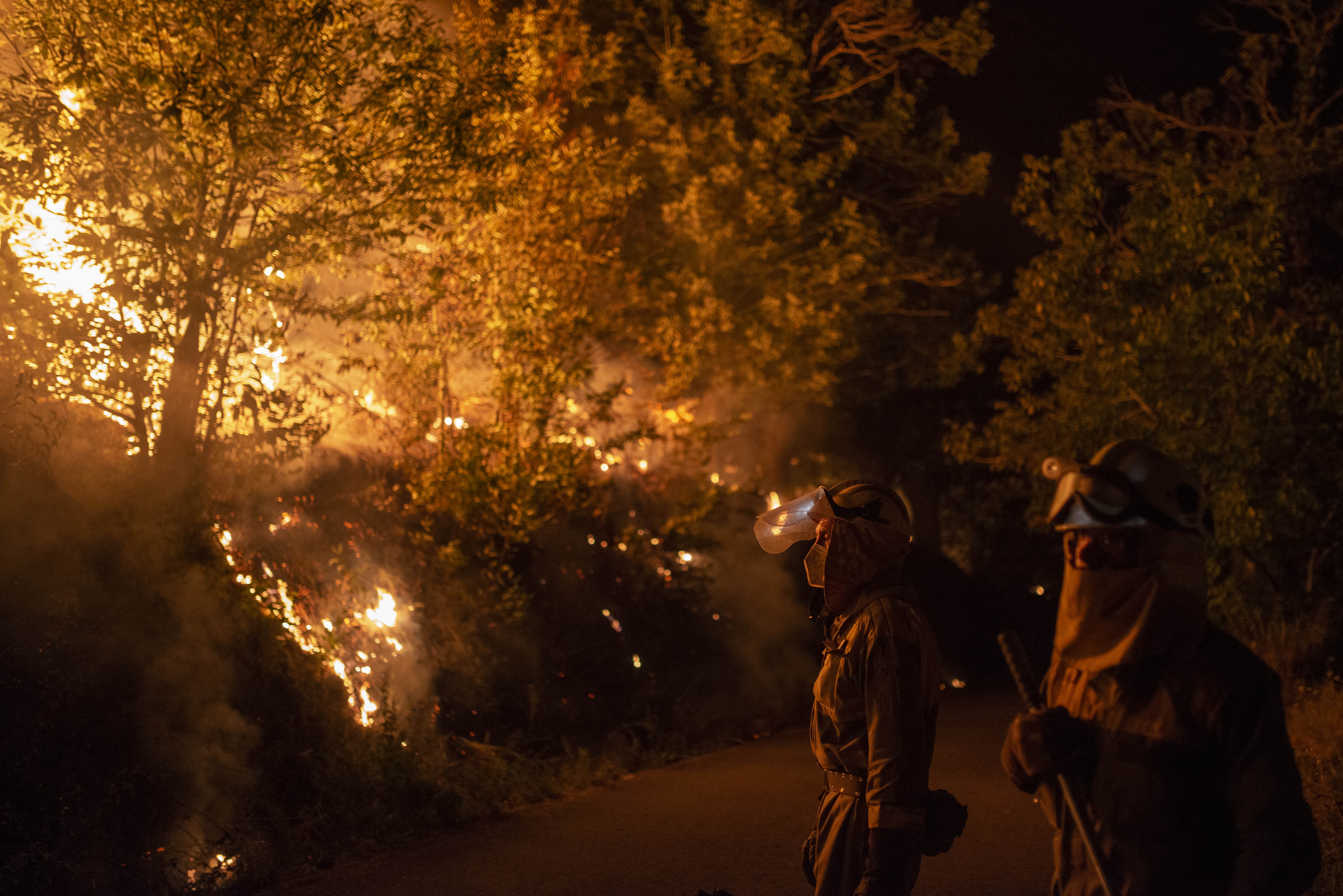 Bomberos tratando de extinguir los incendios forestales declarados en Galicia, con varios fuegos activos, el 18 de julio de 2022. (Foto Prensa Libre: Brais Lorenzo / EFE)