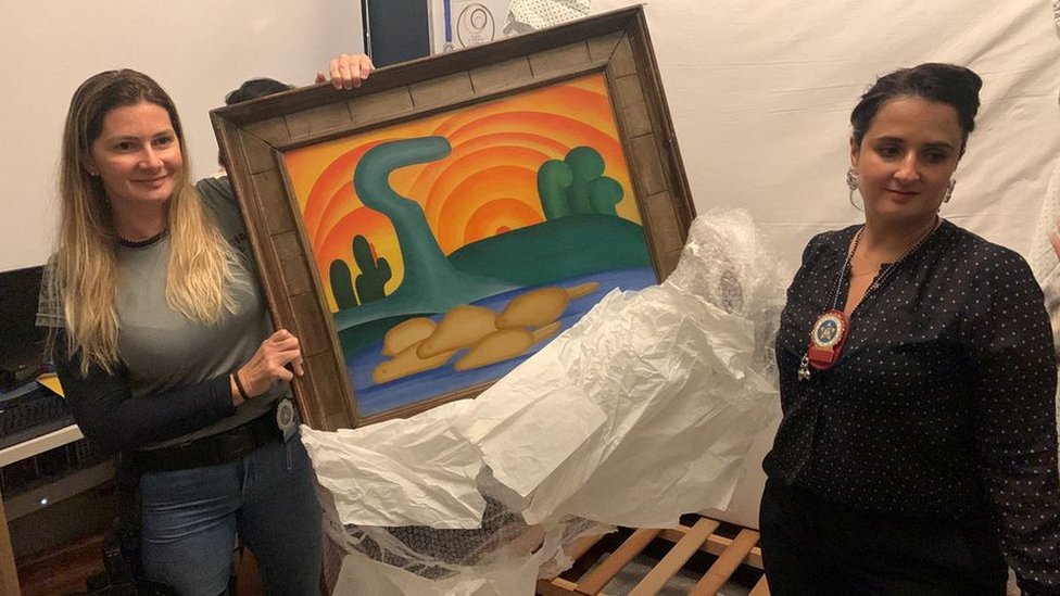 Las autoridades sostienen la pintura de la artista Tarsila do Amaral titulada "Sol Poente" después de que fuera incautada durante una operación policial en Río de Janeiro, Brasil.
REUTERS