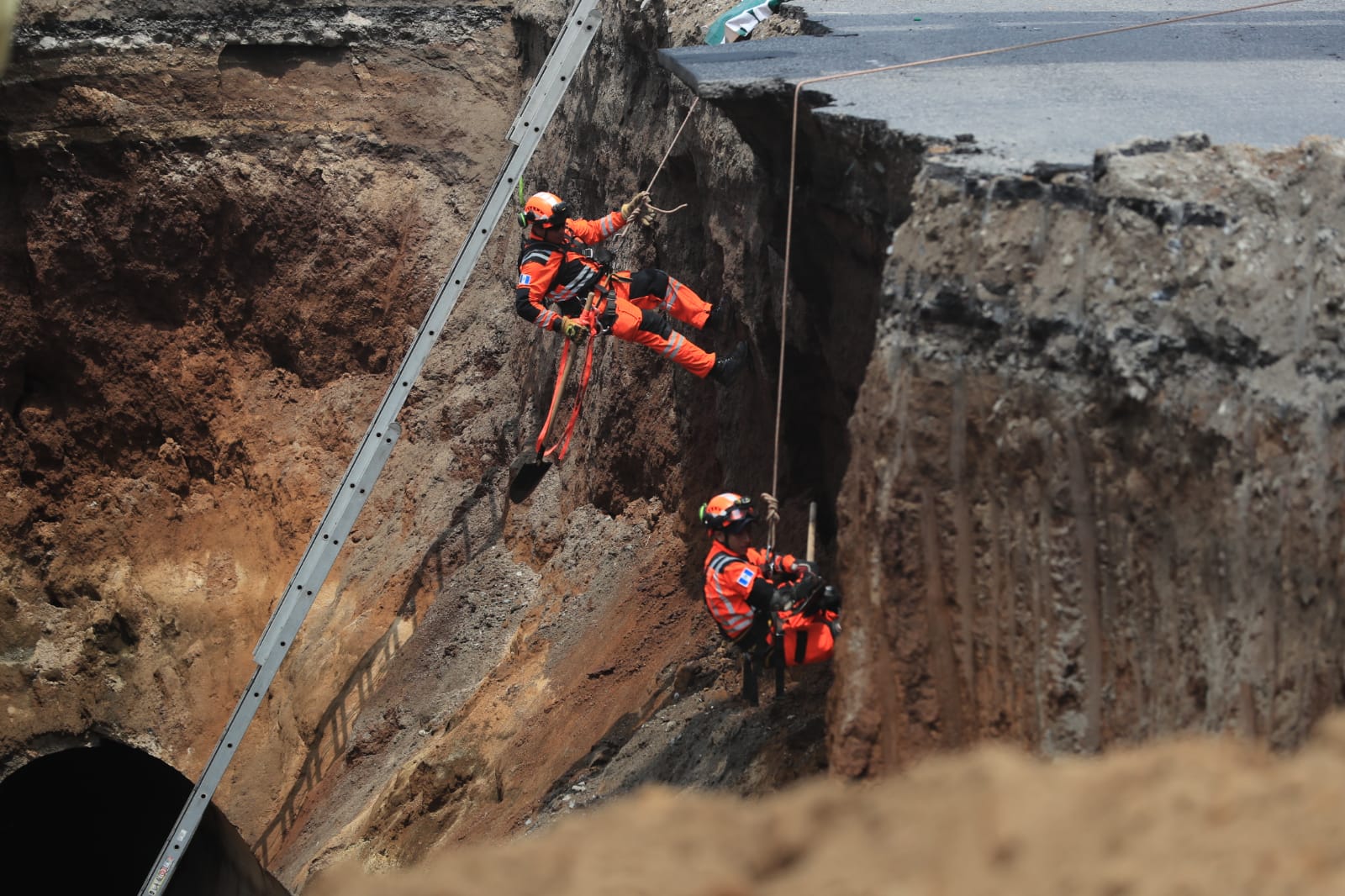 Socorristas descienden al socavón que se formó en Villa Nueva y en el que desaparecieron dos mujeres. (Foto Prensa Libre: Élmer Vargas)