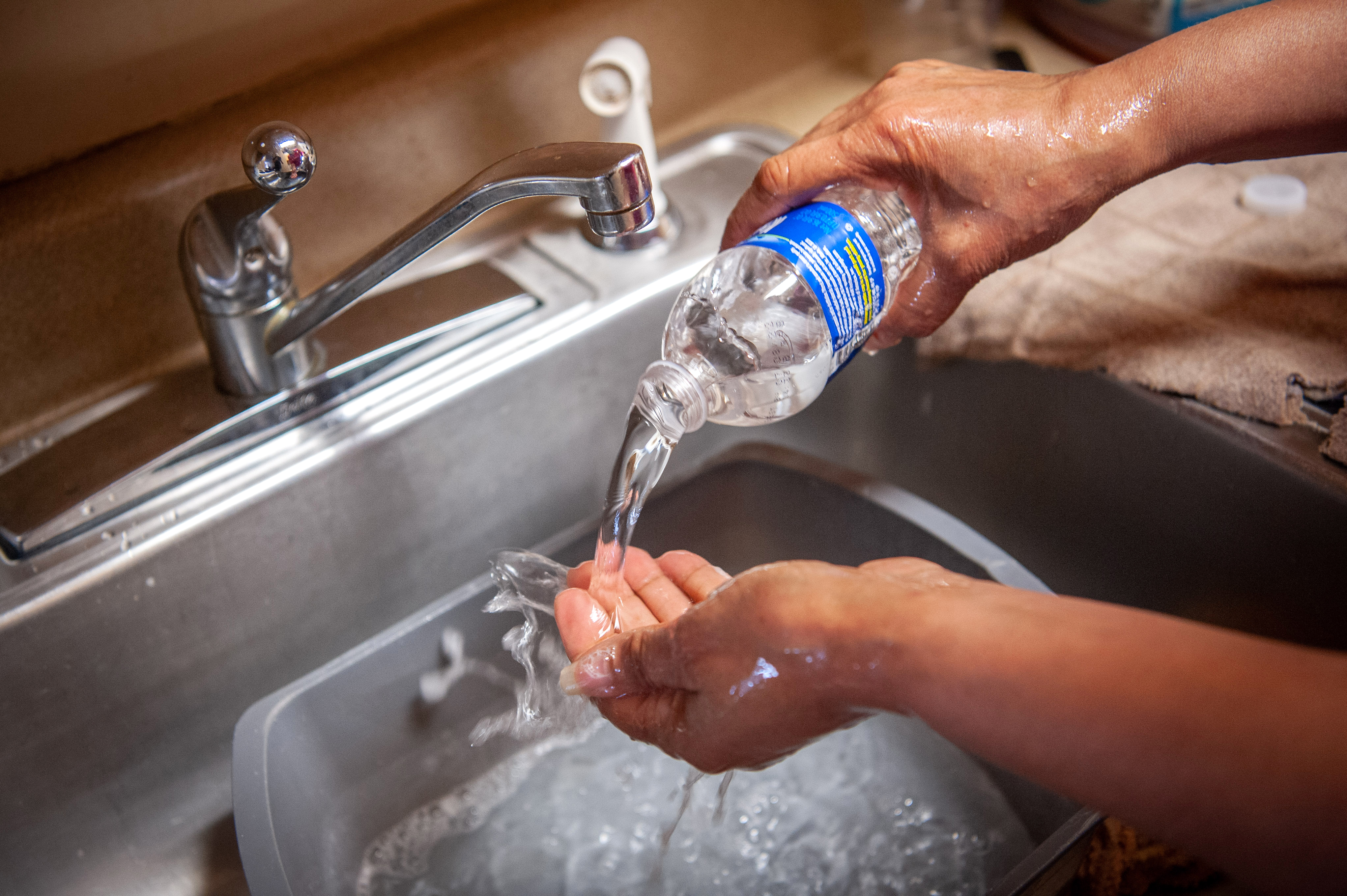 Una residente de Jackson, Misisipi, se lava las manos con agua embotellada en el fregadero de la cocina, el 11 de marzo de 2021.