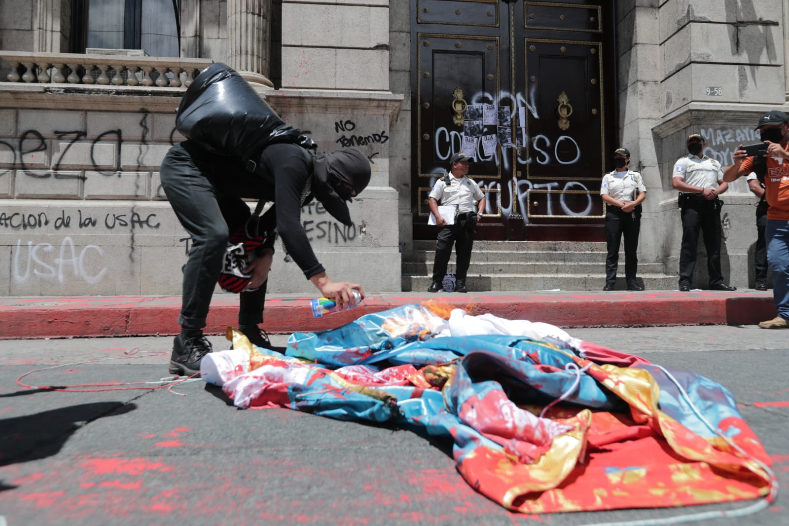 Personas que participaban en una manifestación queman una bandera y dejan pintas en el Congreso de la República. (Imágenes Prensa Libre: E. Vargas)