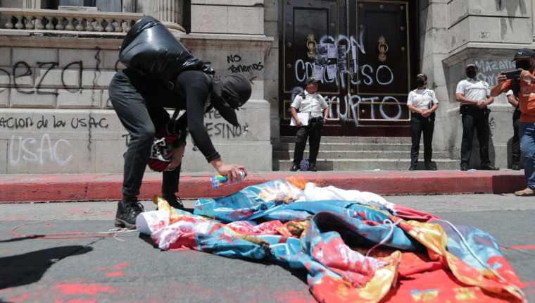 Personas que participaban en una manifestación queman una bandera y dejan pintas en el Congreso de la República. (Imágenes Prensa Libre: E. Vargas)