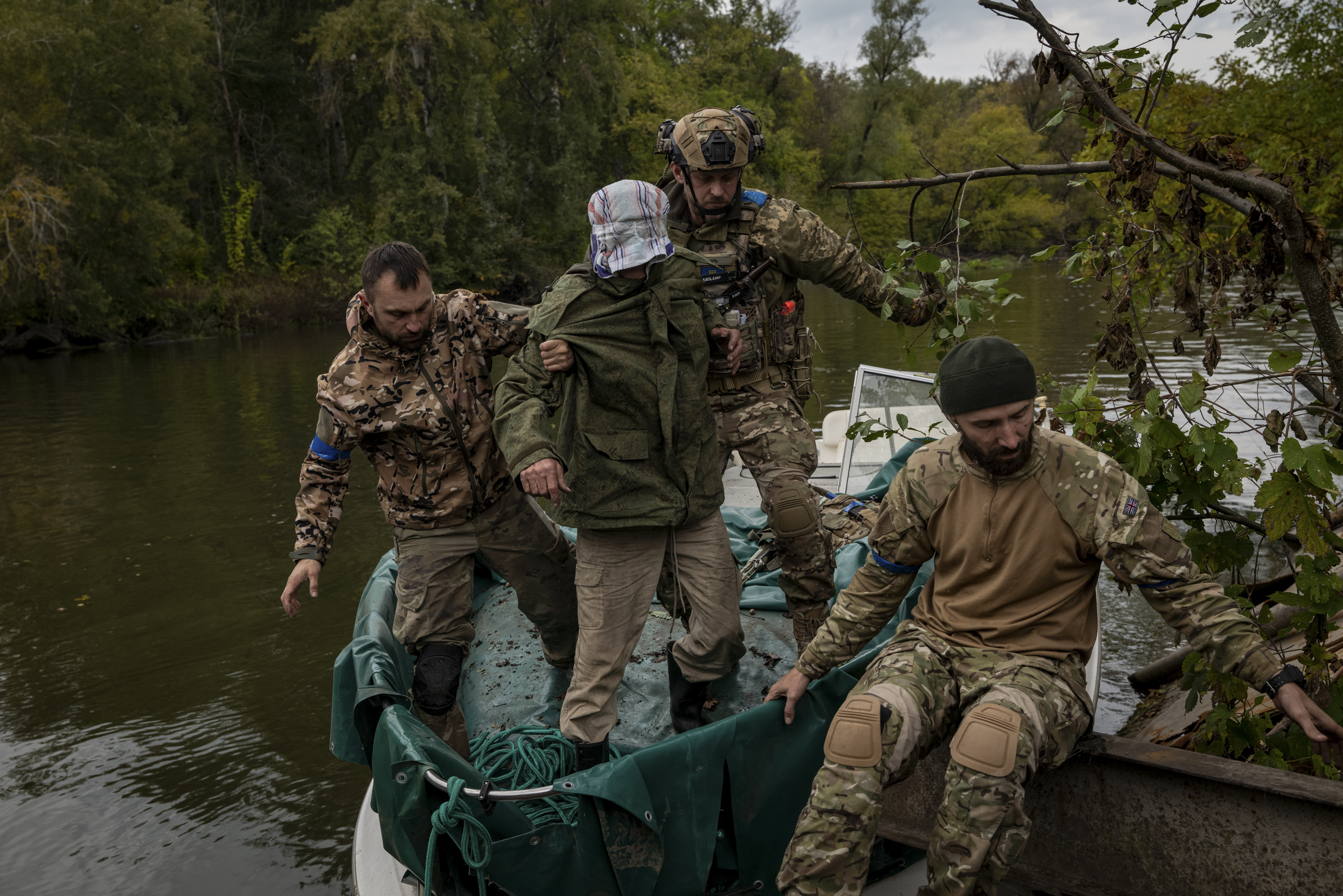 Soldados ucranianos escoltan a un cautivo, capturado en la línea del frente, desde una embarcación hasta la orilla occidental del río Siverskyi Donets, cerca de Lyman, Ucrania, el 27 de septiembre de 2022. (Foto Prensa Libre: Nicole Tung/The New York Times)