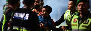 Un niño es auxiliado por las fuerzas de seguridad del estadio donde ocurrió la trágica estampida de aficionados. (Foto Prensa Libre: AFP)