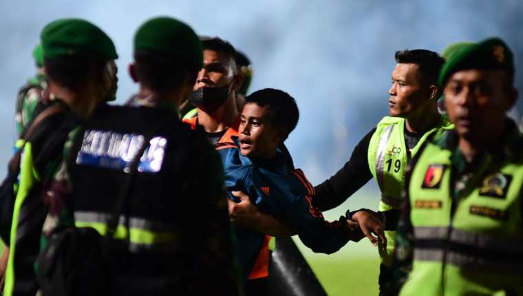 Un niño es auxiliado por las fuerzas de seguridad del estadio donde ocurrió la trágica estampida de aficionados. (Foto Prensa Libre: AFP)