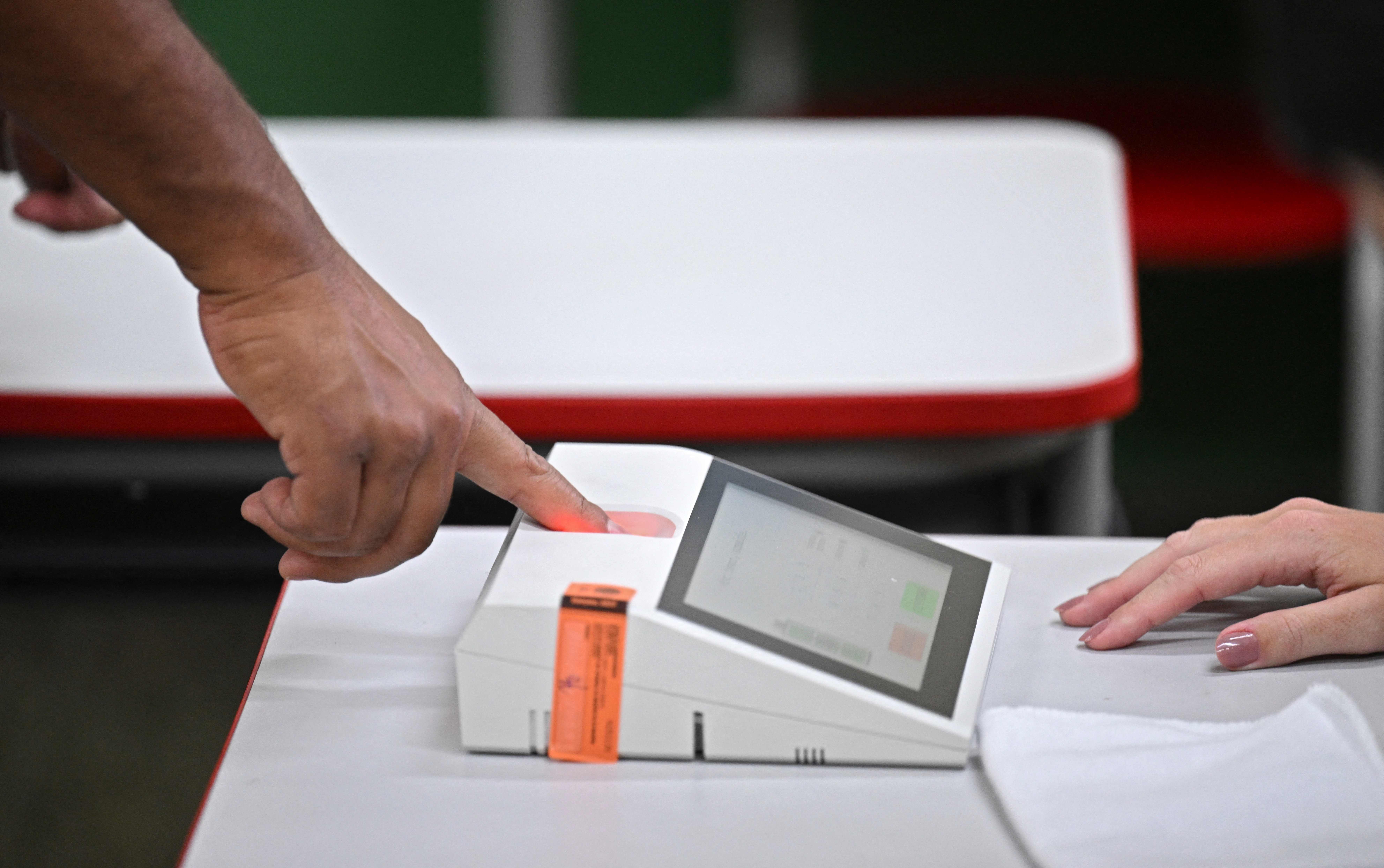 A man puts his finger on an electronic voting machine as he votes at a polling station in Brasilia, on October 30, 2022, during the presidential run-off election. - After a bitterly divisive campaign and inconclusive first-round vote, Brazil elects its next president in a cliffhanger runoff between far-right incumbent Jair Bolsonaro and veteran leftist Luiz Inacio Lula da Silva. (Photo by EVARISTO SA / AFP)
