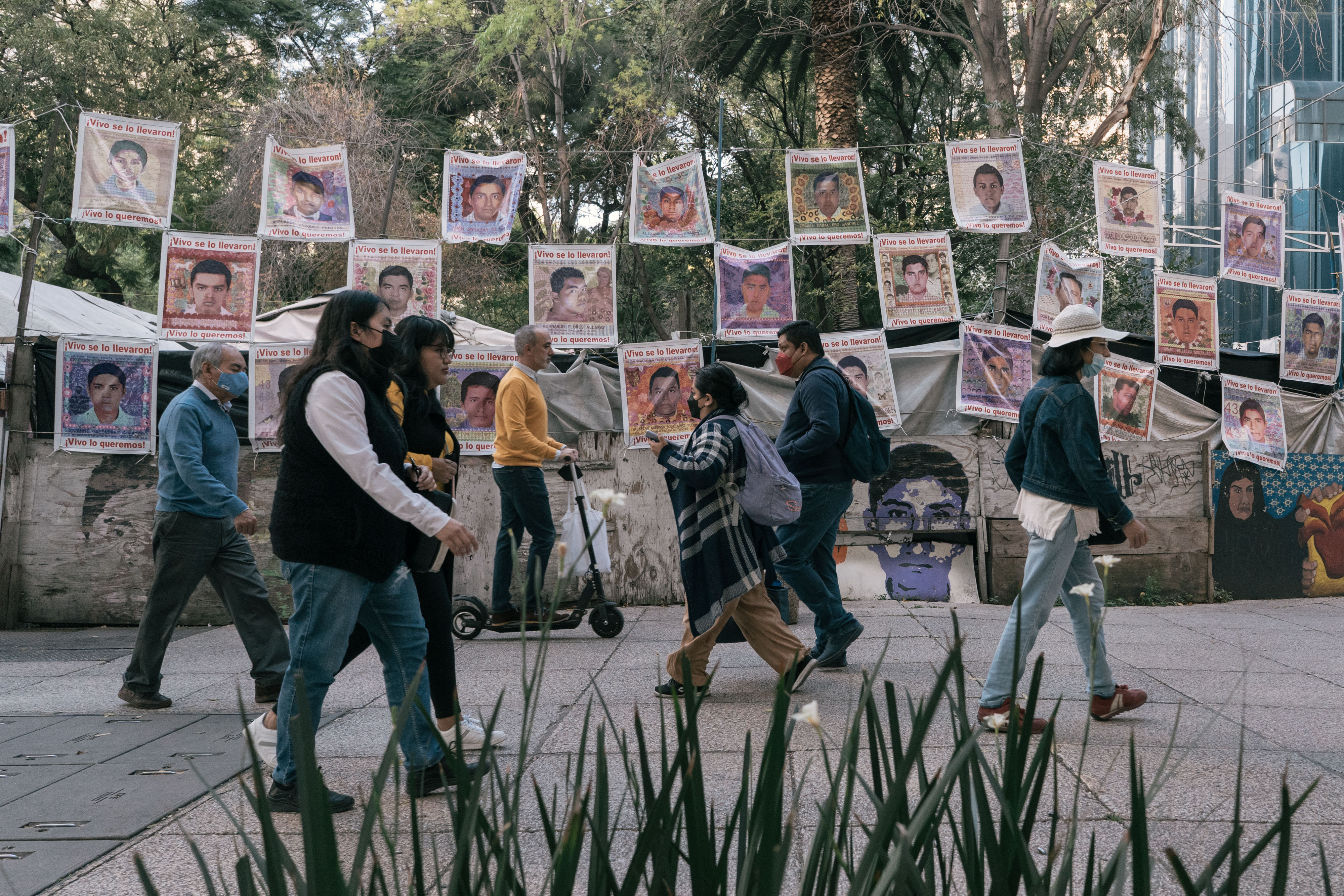 Un grupo de personas camina junto a las imágenes de los 43 estudiantes desaparecidos en 2014, en Ciudad de México, el 24 de octubre de 2022. (Foto Prensa Libre: Luis Antonio Rojas/The New York Times)