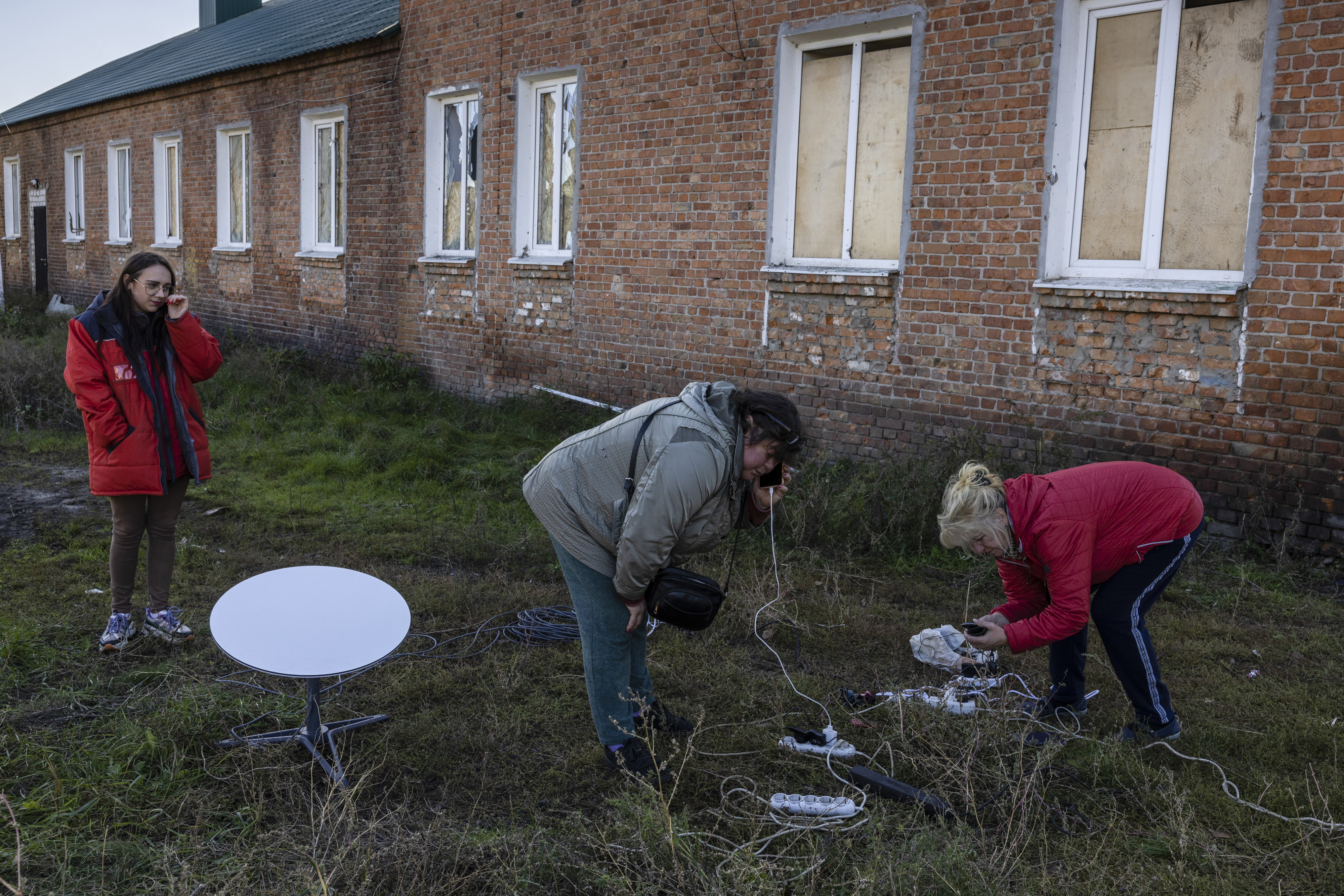 Los residentes utilizan una antena parabólica Starlink y un generador para conectarse a Internet y cargar los teléfonos en Staryi Saltiv, Ucrania, el 17 de octubre de 2022. (Foto Prensa Libre: Ivor Prickett/The New York Times)