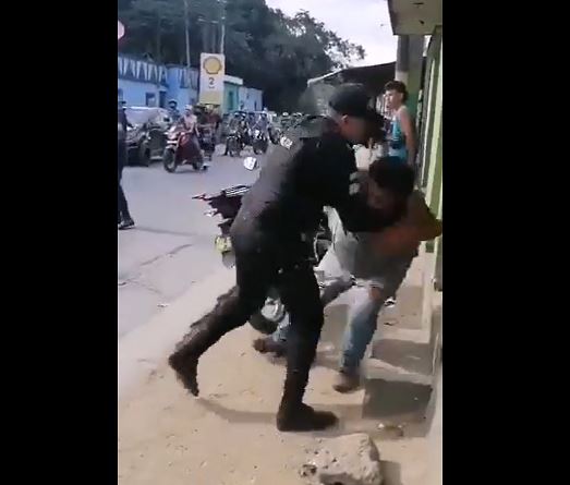 Un policía lanza contra el suelo al comerciante que ya está engrilletado. 