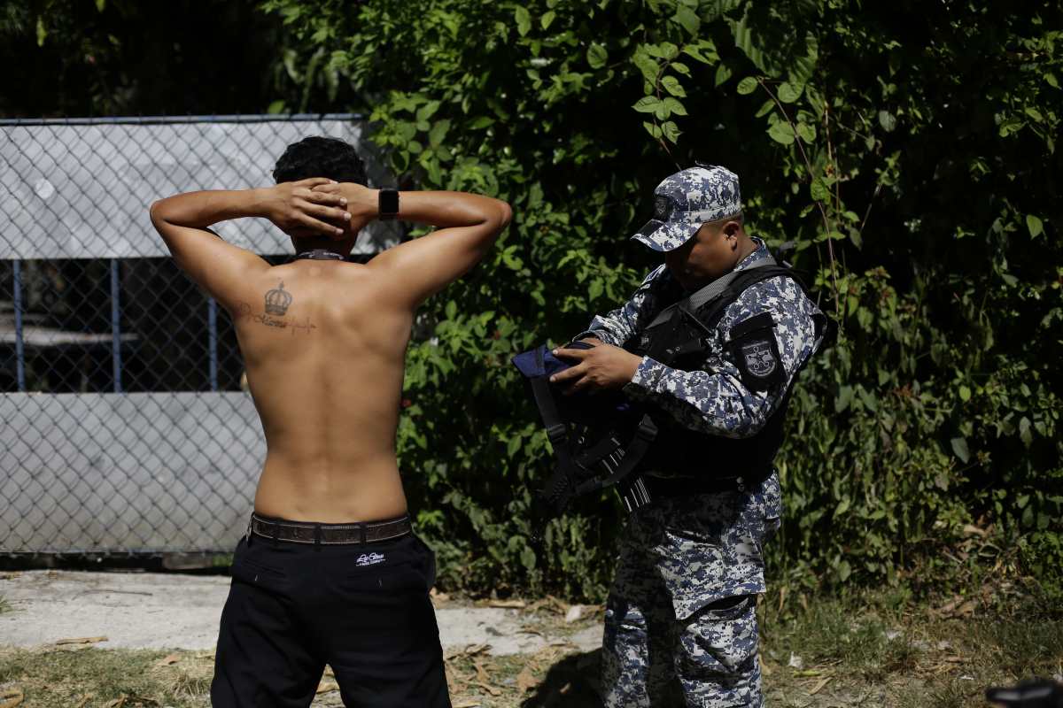 Un policía salvadoreño revisa los papeles de un joven en Soyapango, donde unos 10 mil miembros de la Fuerza Armada y de la Policía Nacional Civil (PNC) fueron desplegados, en el marco de la guerra contra las pandillas que inició en marzo pasado el presidente Nayib Bukele. (Foto Prensa Libre: EFE). 