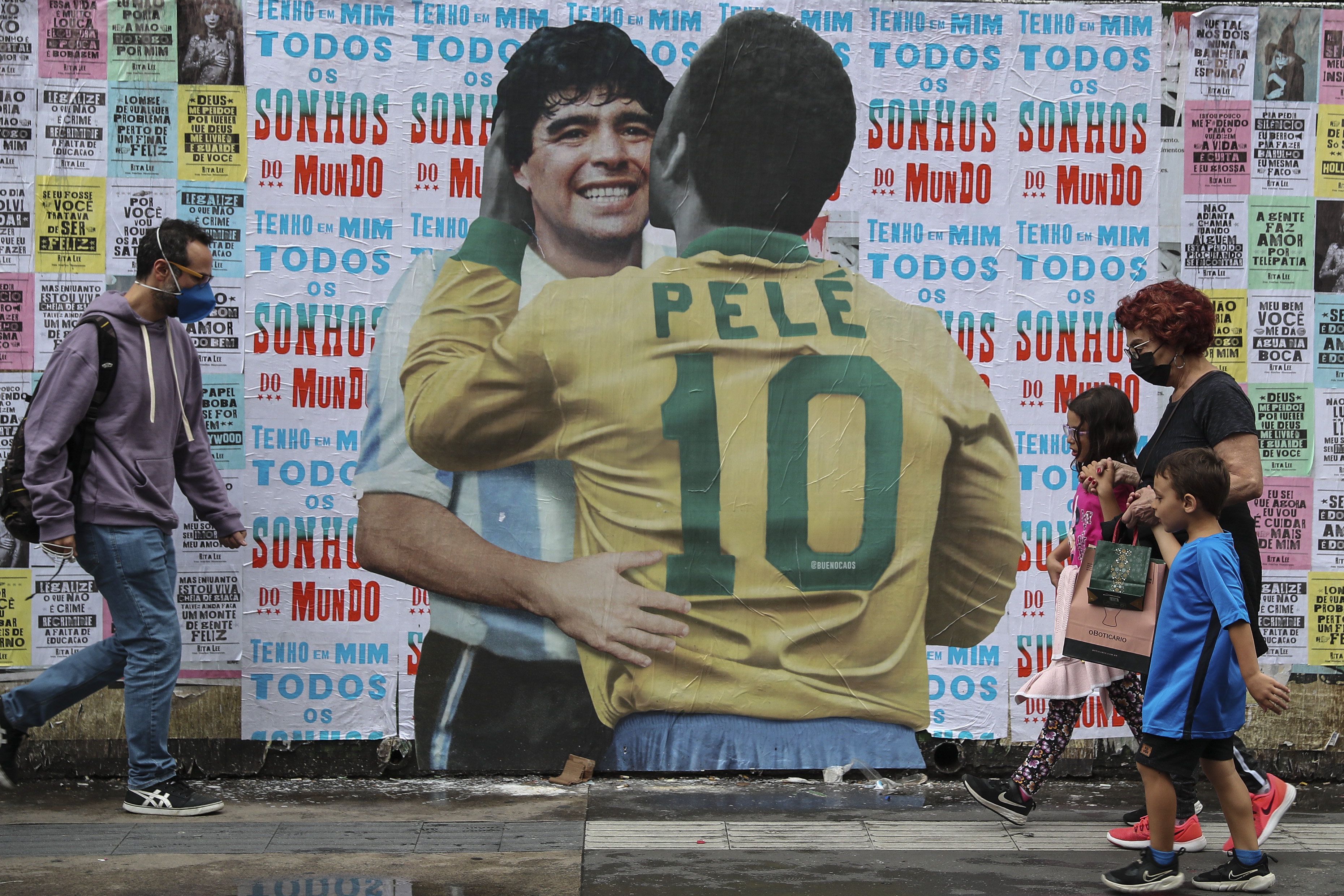 AME2122. SAO PAULO (BRASIL), 20/12/2022.- Varias personas caminan frente a un mural con la imagen de Diego Maradona y Pelé, hoy, en la Avenida Paulista de Sao Paulo (Brasil). Los dos mayores astros de la historia del fútbol, Pelé y Maradona, se funden en un abrazo y un beso en un mural creado por un artista brasileño en la principal avenida de Sao Paulo. EFE/ Sebastiao Moreira