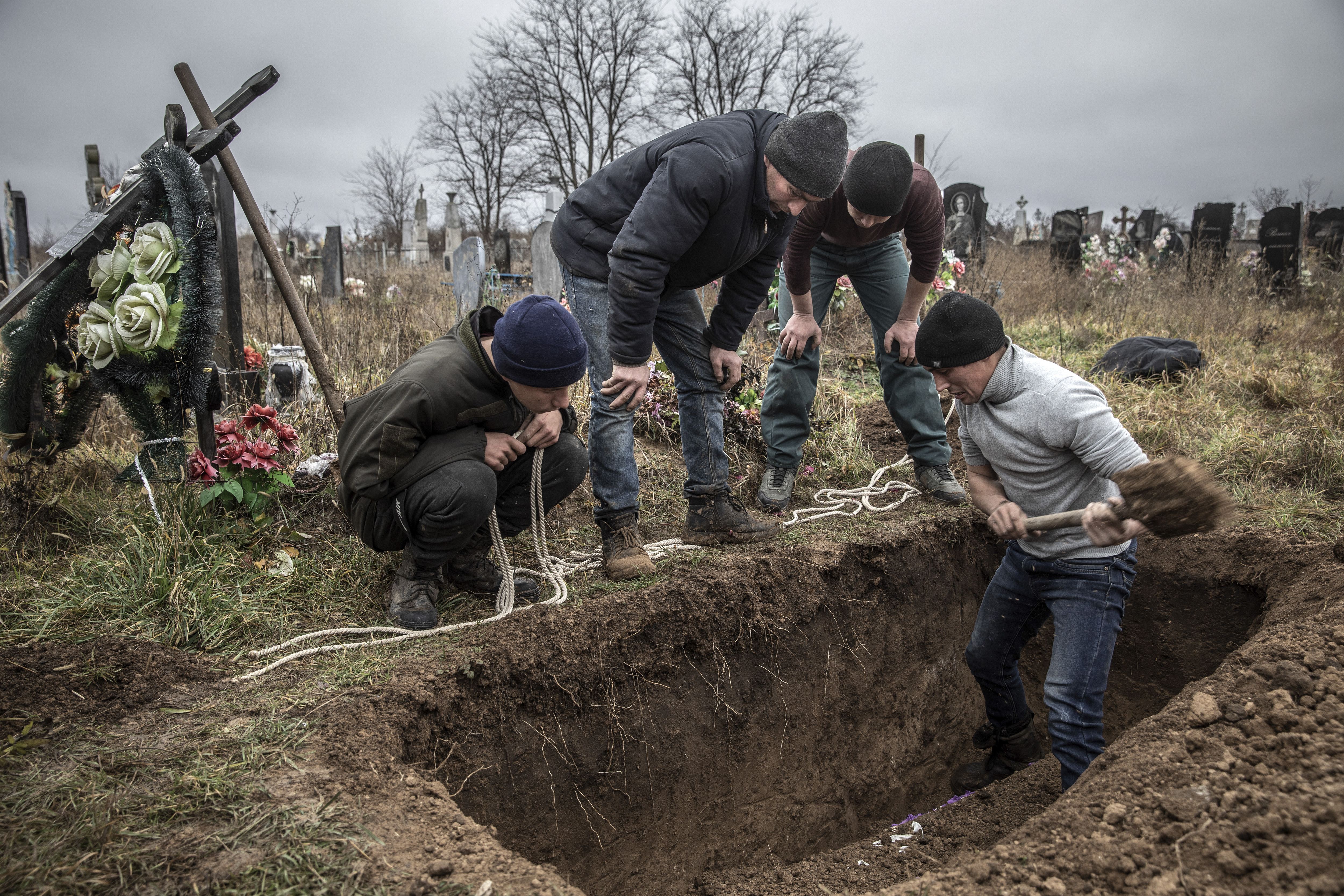 Residentes locales desentierran una tumba para ayudar a la policía y a los investigadores de crímenes de guerra a exhumar el cuerpo de una niña de 15 años, que, según los residentes locales, había sido ejecutada por las fuerzas, en la recién liberada aldea de Pravdyne, Ucrania, el 29 de noviembre de 2022. (Foto Prensa Libre: Finbarr O'Reilly/The New York Times)
