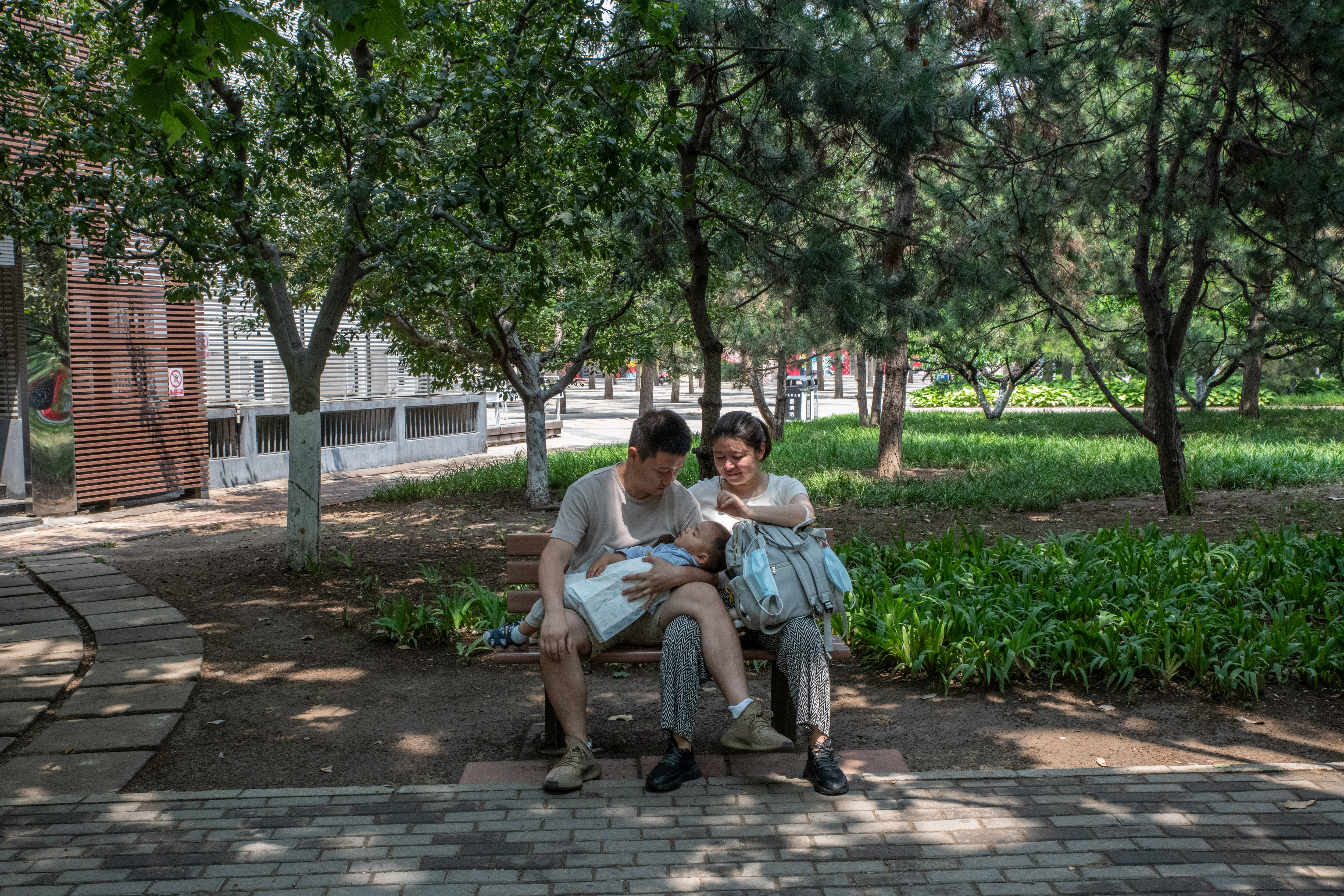 Dos padres con un bebé en brazos en un parque de Pekín, el 12 de junio de 2022. (Foto Prensa Libre: Gilles Sabrié/The New York Times)