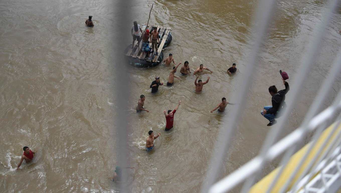 Migrantes saltan al río Suchiate desde el puente fronterizo Guatemala-México en Tecún Umán cuando una "avalancha" intentaba cruzar en caranava a finales de 2018. (Foto Prensa Libre: AFP)