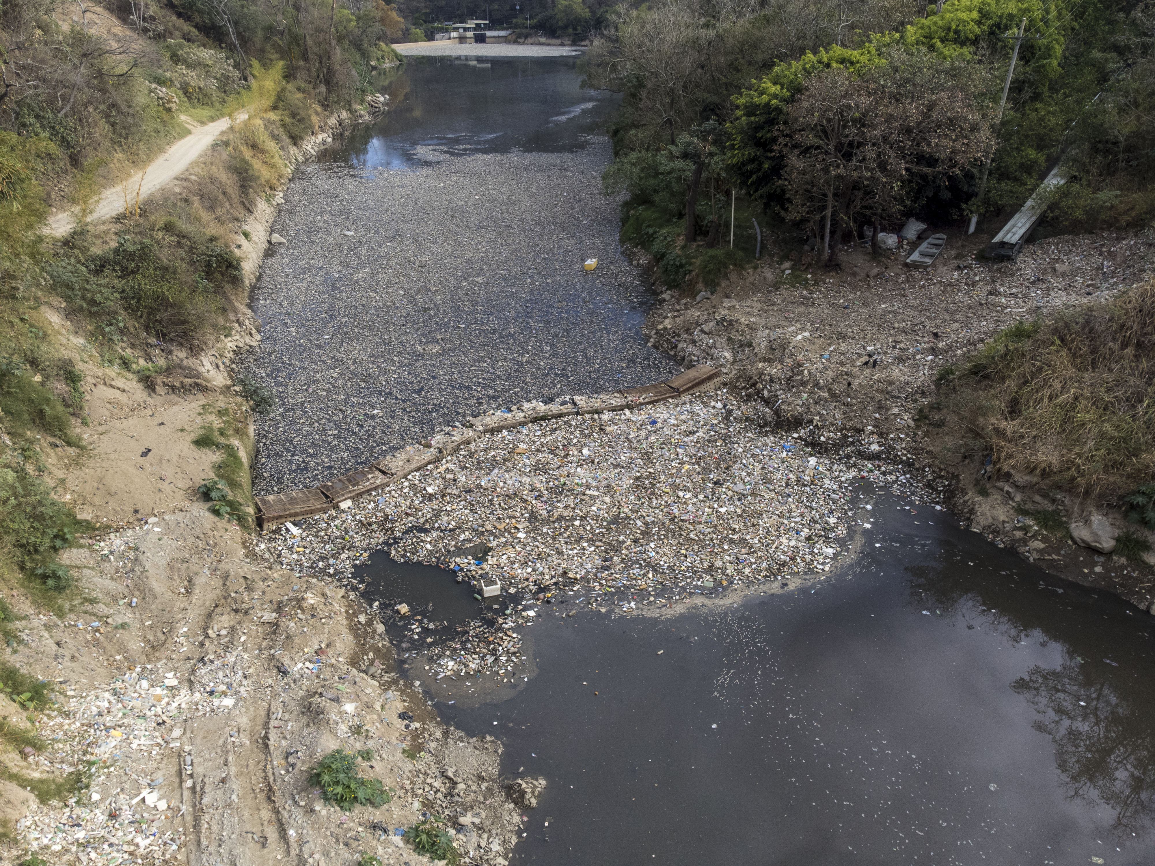 ACOMPAÑA CRÓNICA AME3154. CHINAUTLA (GUATEMALA), 17/03/2023.- Fotografía con drone del 10 de marzo 2023, de una biobarda que intenta contener cientos de toneladas de basura que atraviesan el río Las Vacas, provenientes de la Ciudad de Guatemala, en Chinautla (Guatemala). Guatemala tiene el doble de disponibilidad de agua que el promedio mundial, pero el 90 % de sus fuentes están contaminadas y millones de personas sufren un calvario diariamente para obtenerla, debido a décadas de una deficiente administración estatal. EFE/Esteban Biba