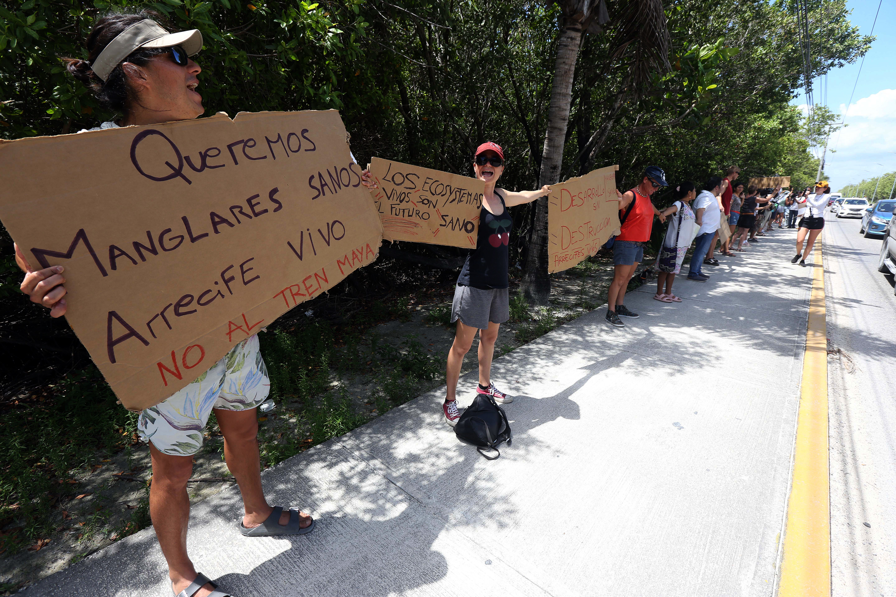 Pobladores y grupos de ambientalistas que se manifiestan de manera pacífica con una cadena humana contra el Tren Maya por la devastación de arrecifes y manglares, en Puerto Morelos, Quintana Roo (México). Organizaciones ambientalistas realizaron una cadena humana en Puerto Morelos, al sureste de México, en protesta por los daños ambientales causados por las obras del Tren Maya y por el riesgo que representan para los ecosistemas de arrecifes el traslado de la piedra porfirita importada de Cuba. EFE/Alonso Cupúl