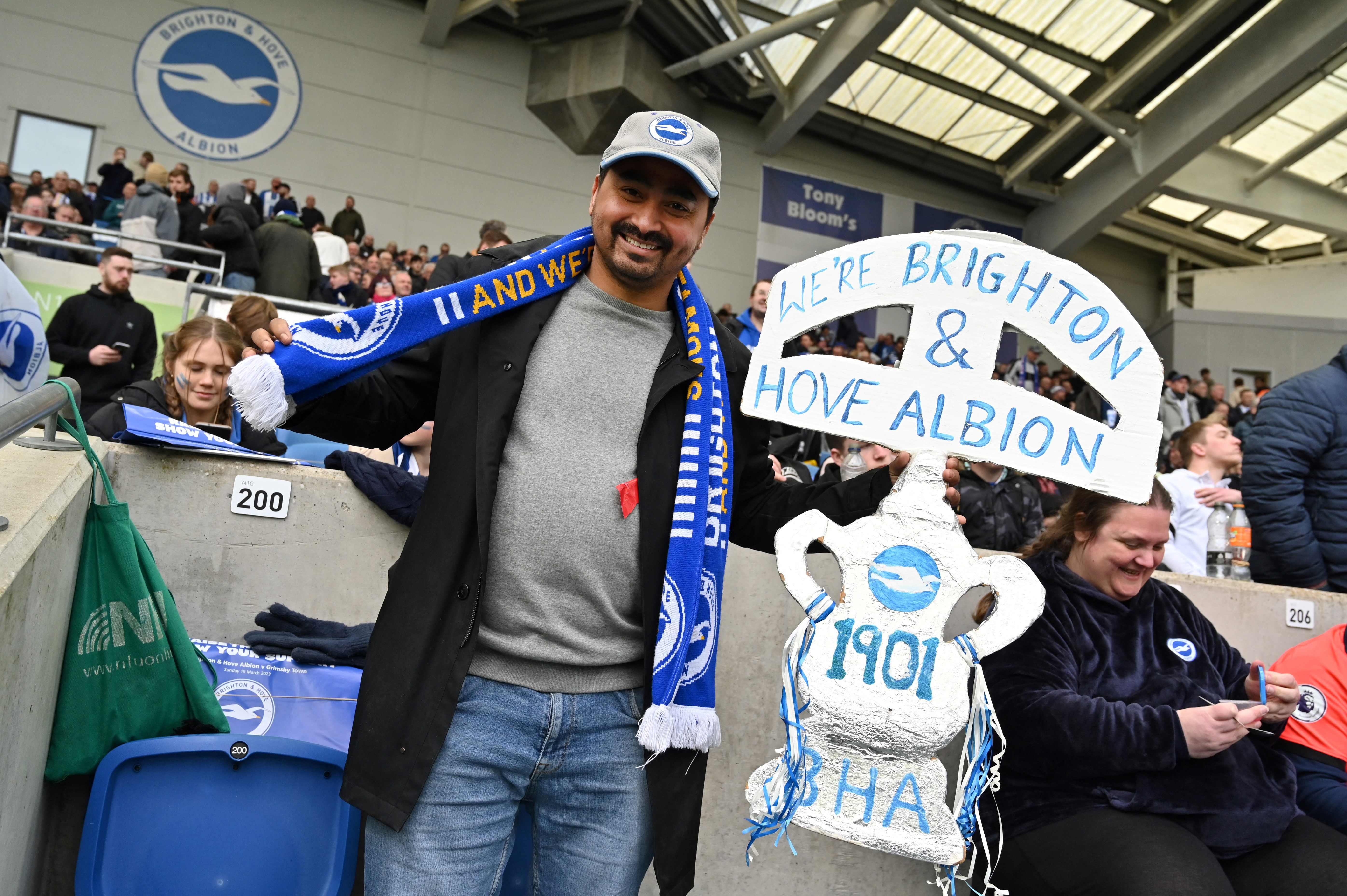 A Brighton's supporter poses with a board in the shape of a trophy during the English FA Cup quarter-final football match between Brighton & Hove Albion and Grimsby Town at the Amex stadium in Brighton, on the south coast of England on March 19, 2023. (Photo by Glyn KIRK / AFP) / RESTRICTED TO EDITORIAL USE. No use with unauthorized audio, video, data, fixture lists, club/league logos or 'live' services. Online in-match use limited to 120 images. An additional 40 images may be used in extra time. No video emulation. Social media in-match use limited to 120 images. An additional 40 images may be used in extra time. No use in betting publications, games or single club/league/player publications. /