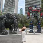 A visitor takes photographs of life-sized statues of Transformers' characters Optimus Prime and Optimus Primal displayed as part of a world tour at Garden by the Bay in Singapore on March 21, 2023. (Photo by Roslan RAHMAN / AFP)